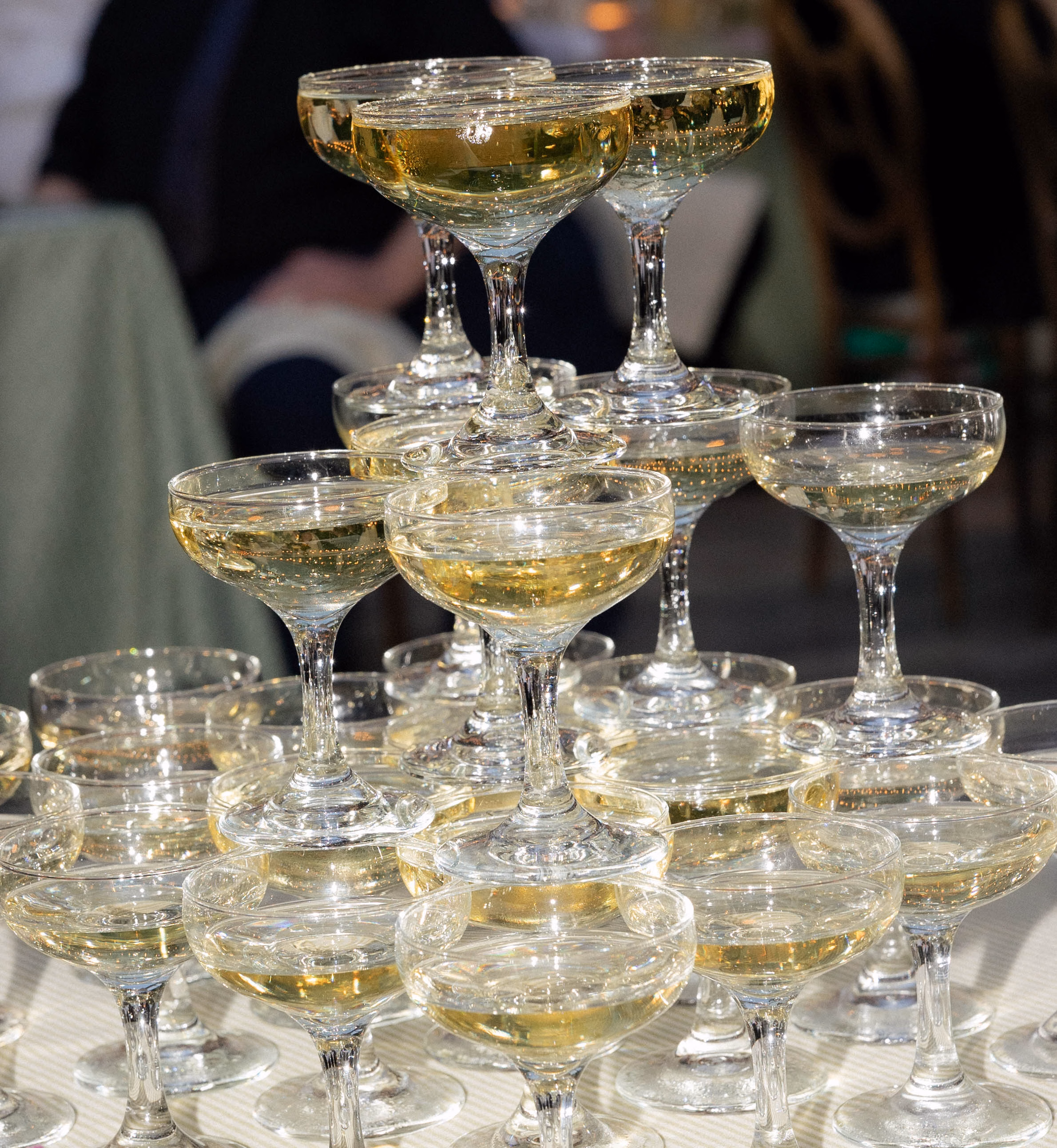 Luxury wedding glassware rentals in Milwaukee, WI, by Tablescapes Event Rentals, featuring a multi-tiered champagne coupe tower filled with bubbly champagne at a reception.