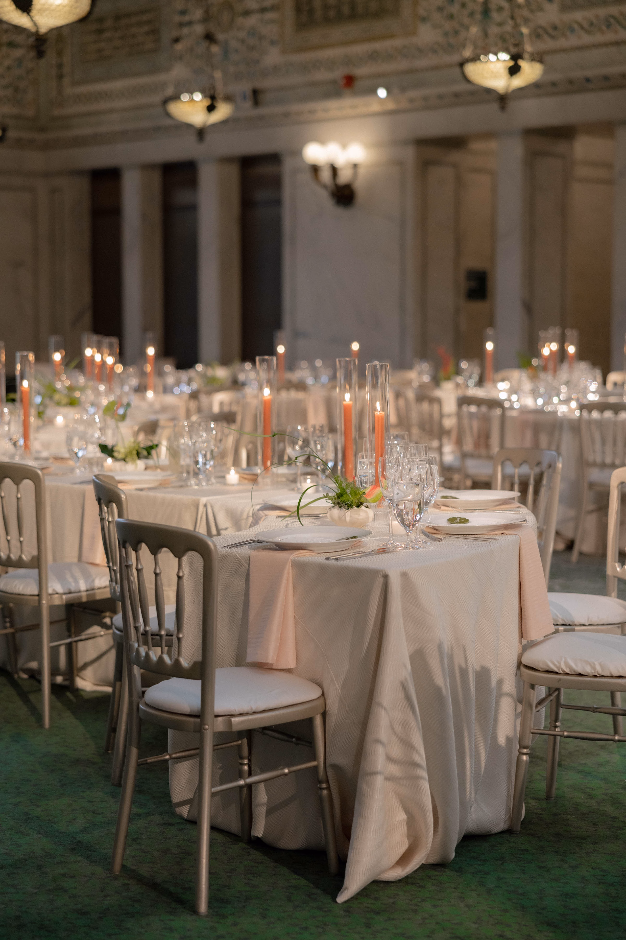 Elegant ballroom wedding reception rentals in Milwaukee, WI, by Tablescapes Event Rentals, showcasing ivory textured tablecloths, silver Chiavari chairs with white cushions, glass taper candle holders, and fine dining stemware.