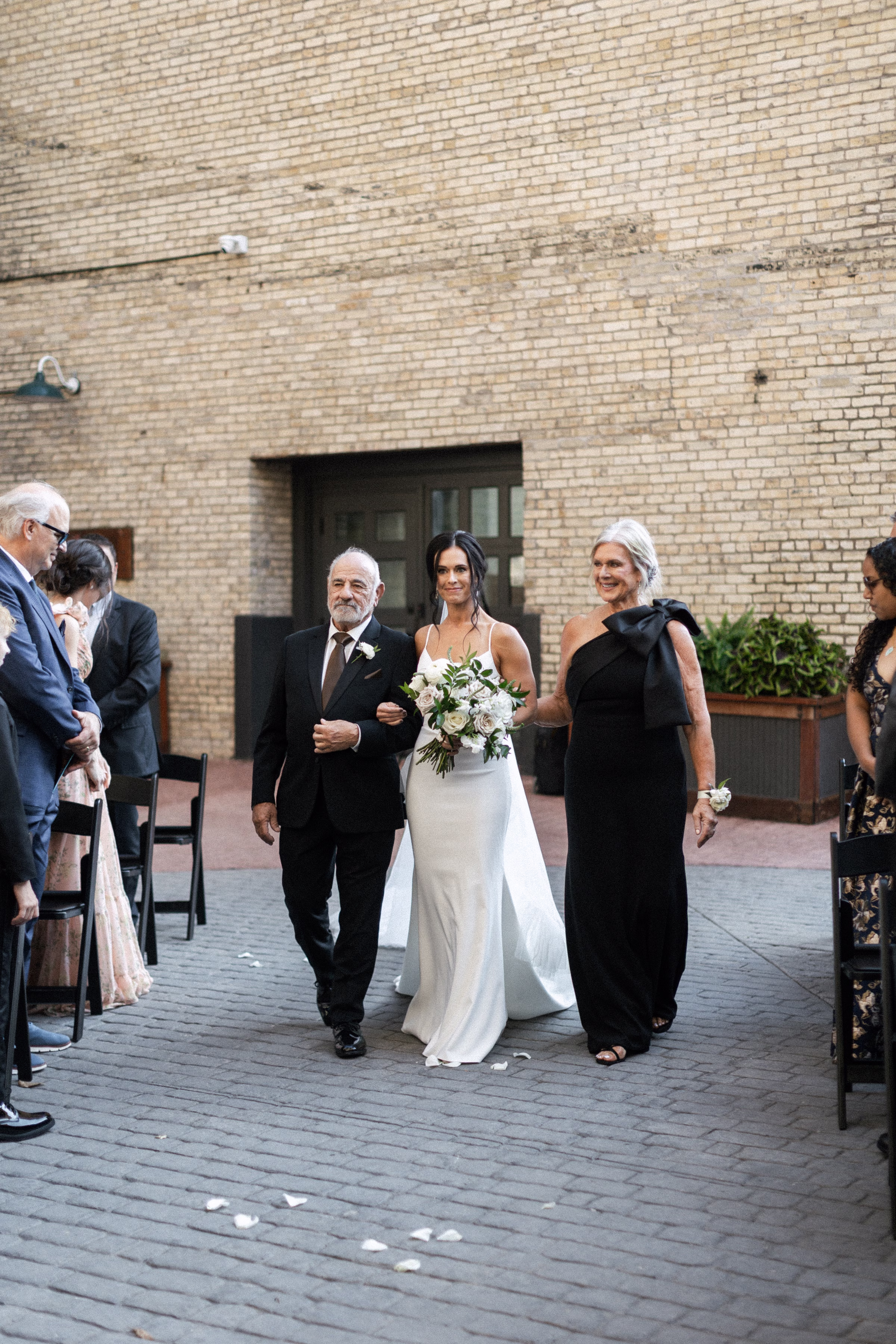 bride Courtney walks down the aisle, escorted by her parents