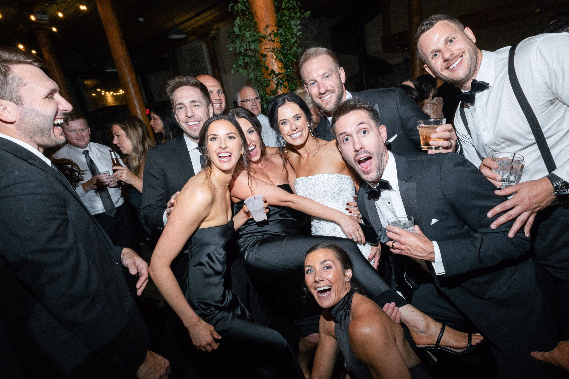 the couple pose for a group photo on the dance floor at their wedding reception