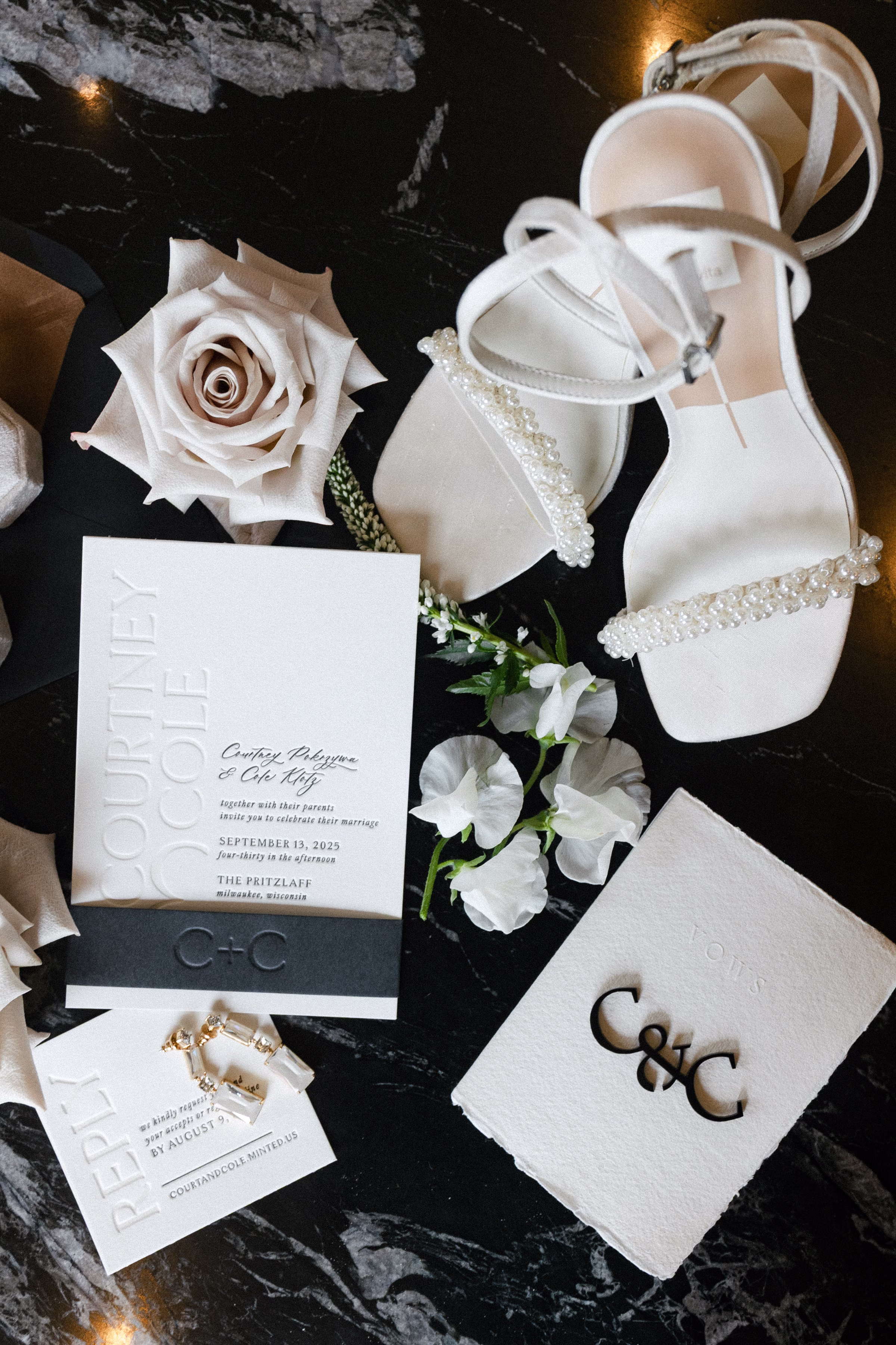 a wedding invitation suite from Bay View Printing Co., with letterpress, also placed beside accessories like shoes and earrings