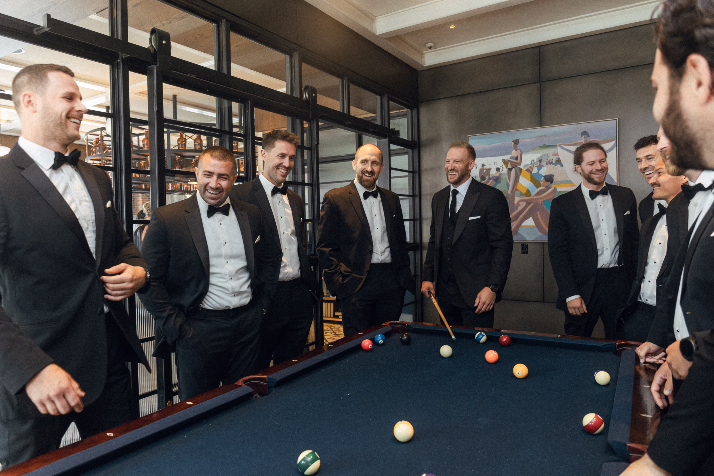 the groom and groomsmen play pool as they prepare for the wedding day