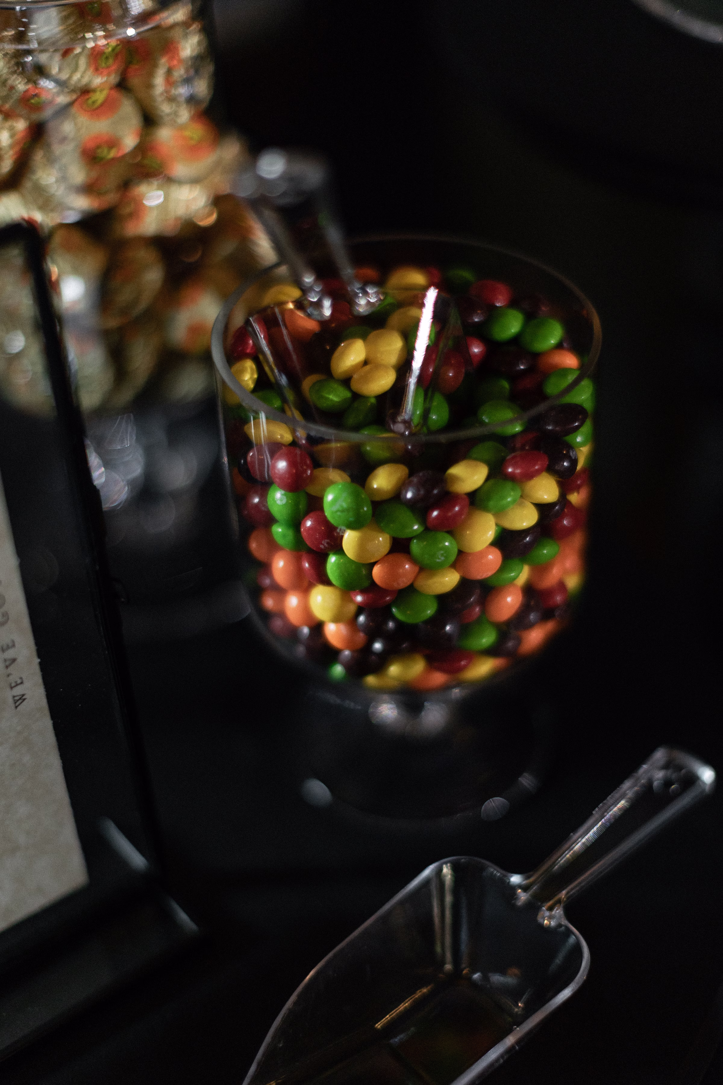 a close up of colorful candies in a jar with a scoop