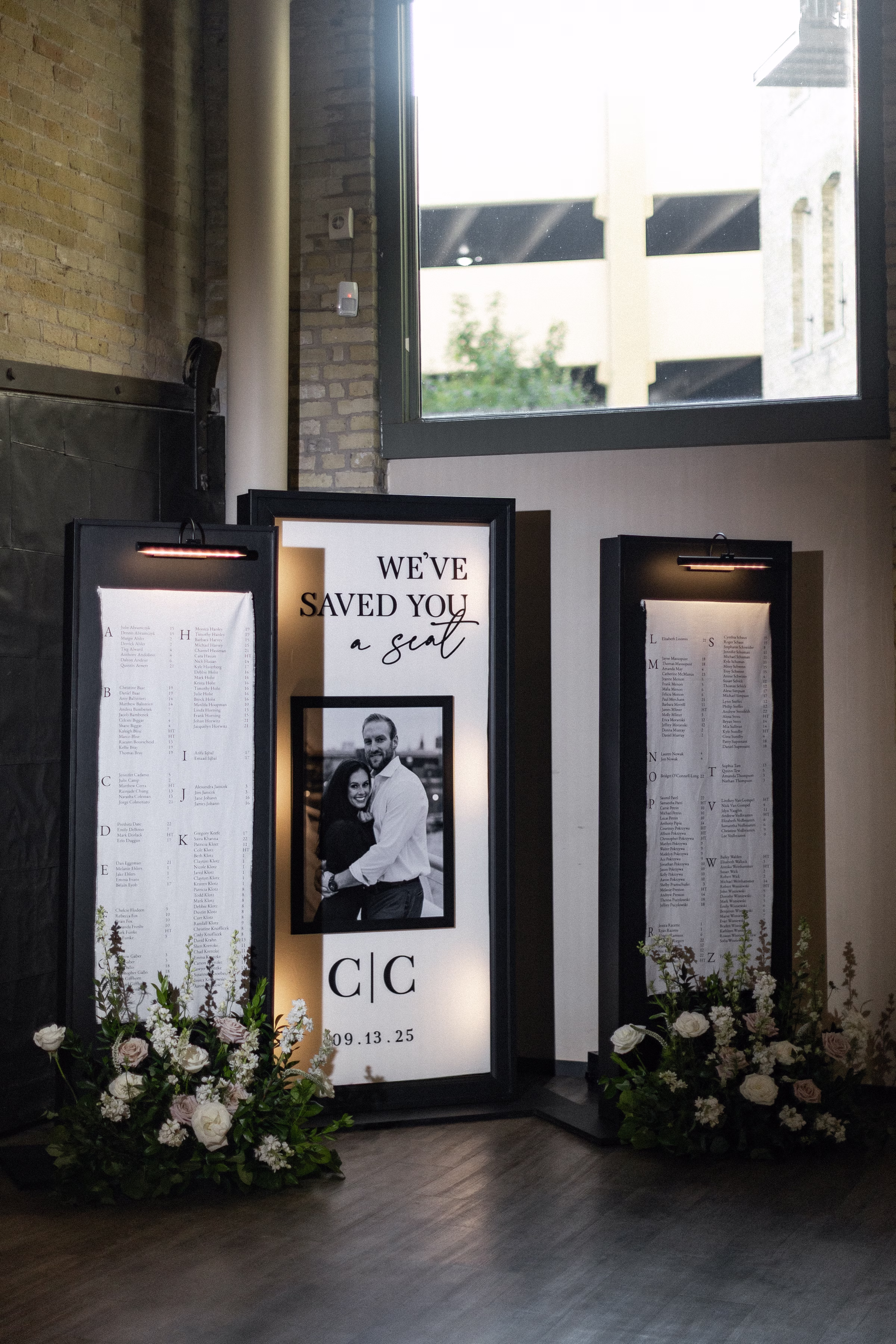 a three-part welcome sign and seating chart featuring a black and white couple photograph and surrounded by florals