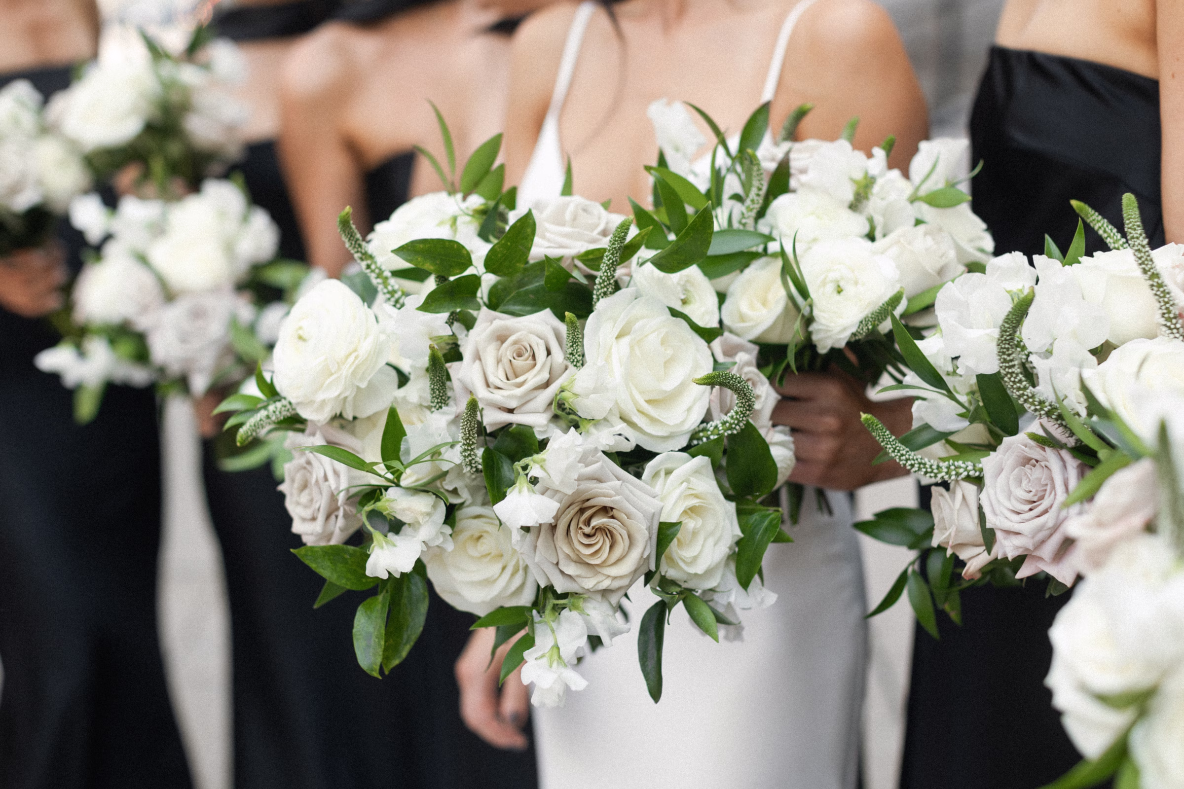 a white bridal bouquet of roses, veronica, and greenery