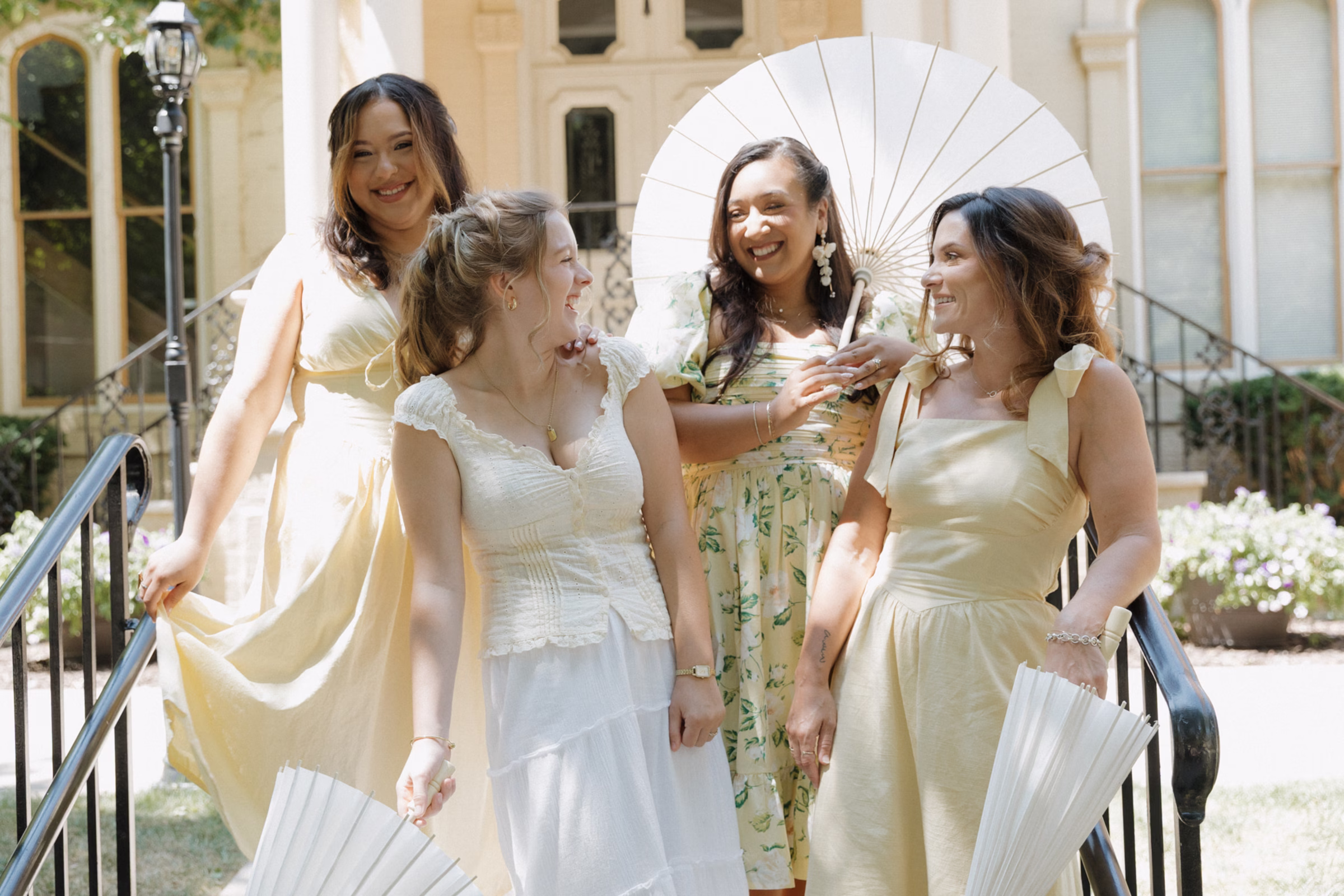 the models pose in front of The Fitzgerald, holding parasols to playfully shield themselves from the sun