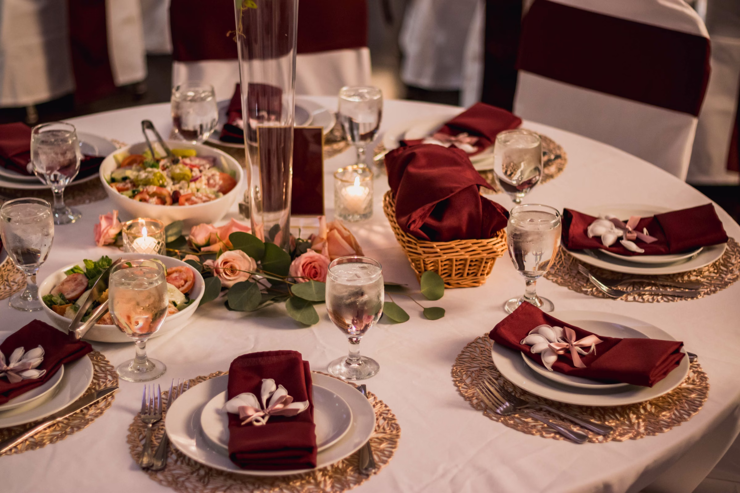 Wedding dinner table with maroon accents and food by Prime Minister Catering