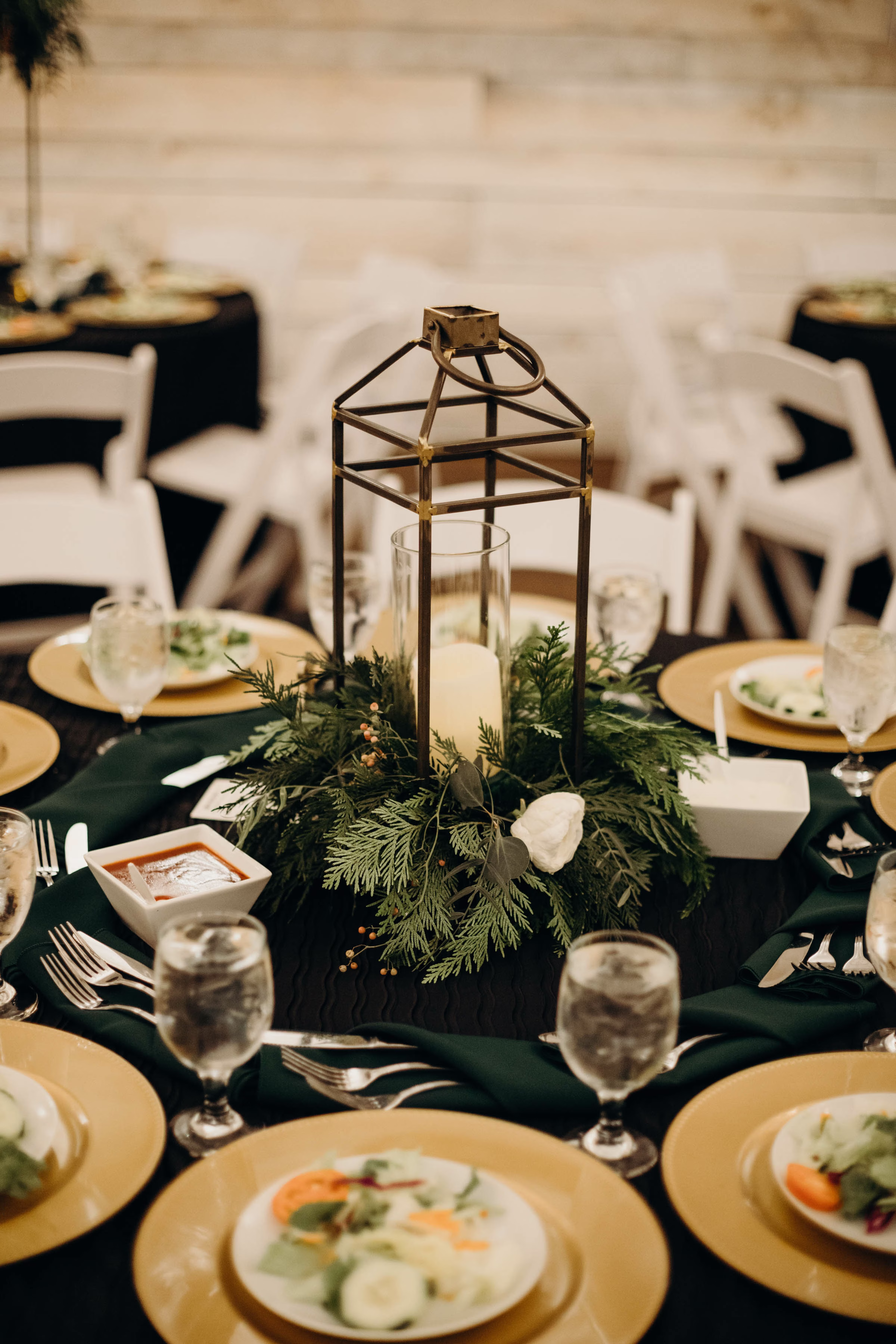 Winter wedding tablescape with candle lamp, evergreen and gold accents, salad catered by Prime Minister Catering
