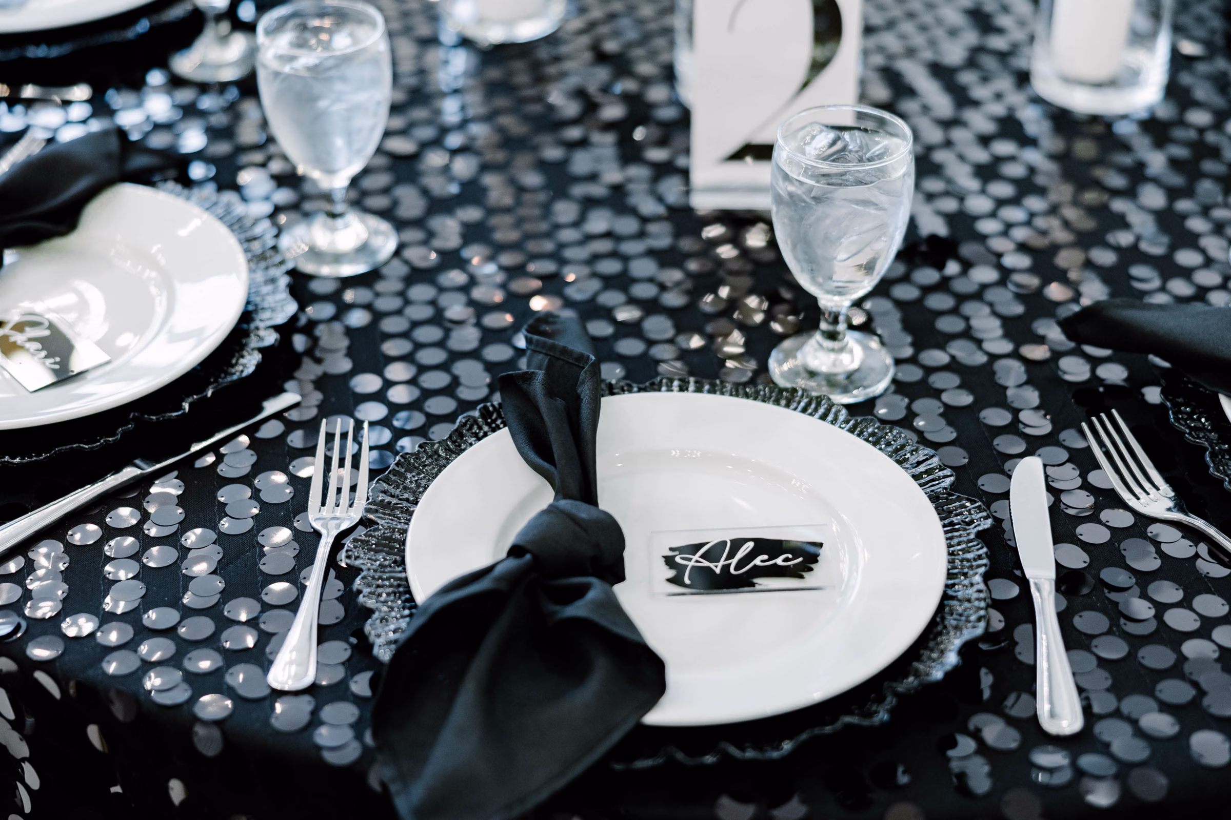 Elegant black and white wedding table setting with charger plate and name card, catered by Prime Minister Catering