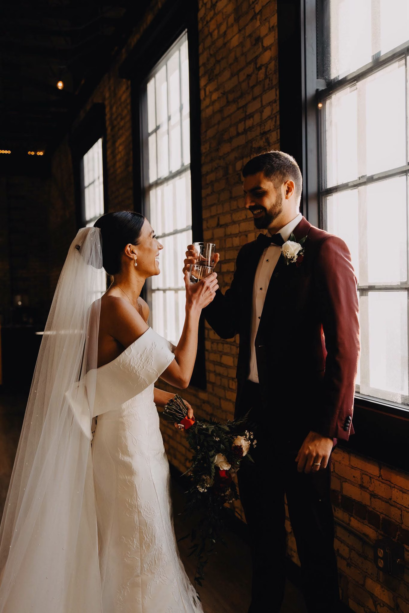 The Berkshire Sheboygan wedding venue — bride and groom toasting with drinks inside the industrial brick loft space