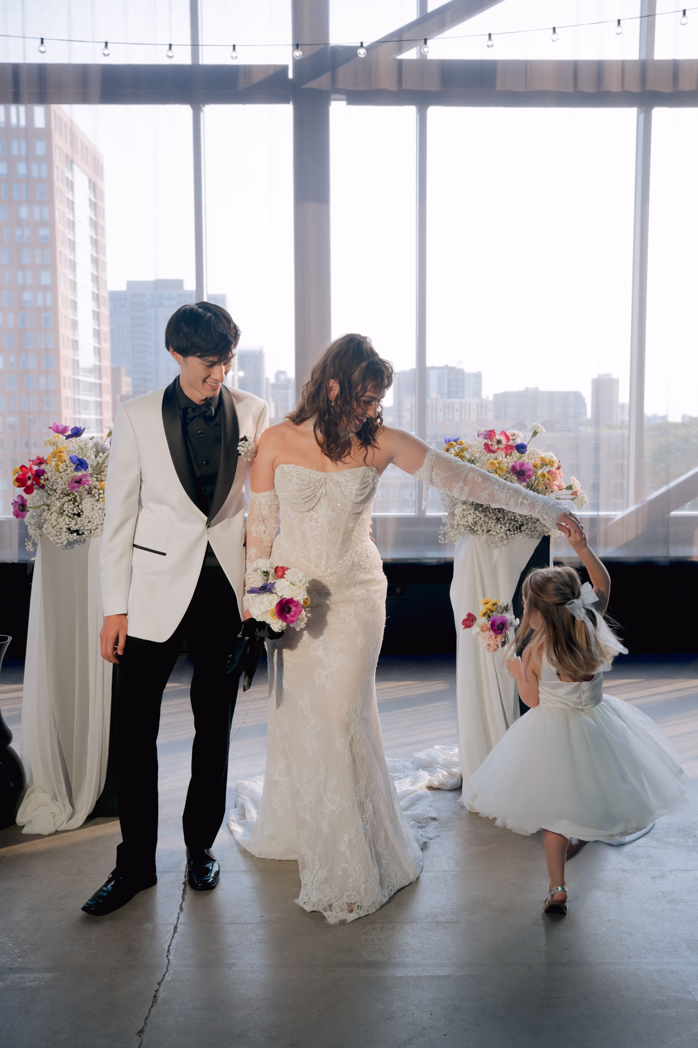 the bride and groom stand at the ceremony space while the bride twirls around a young flower girl