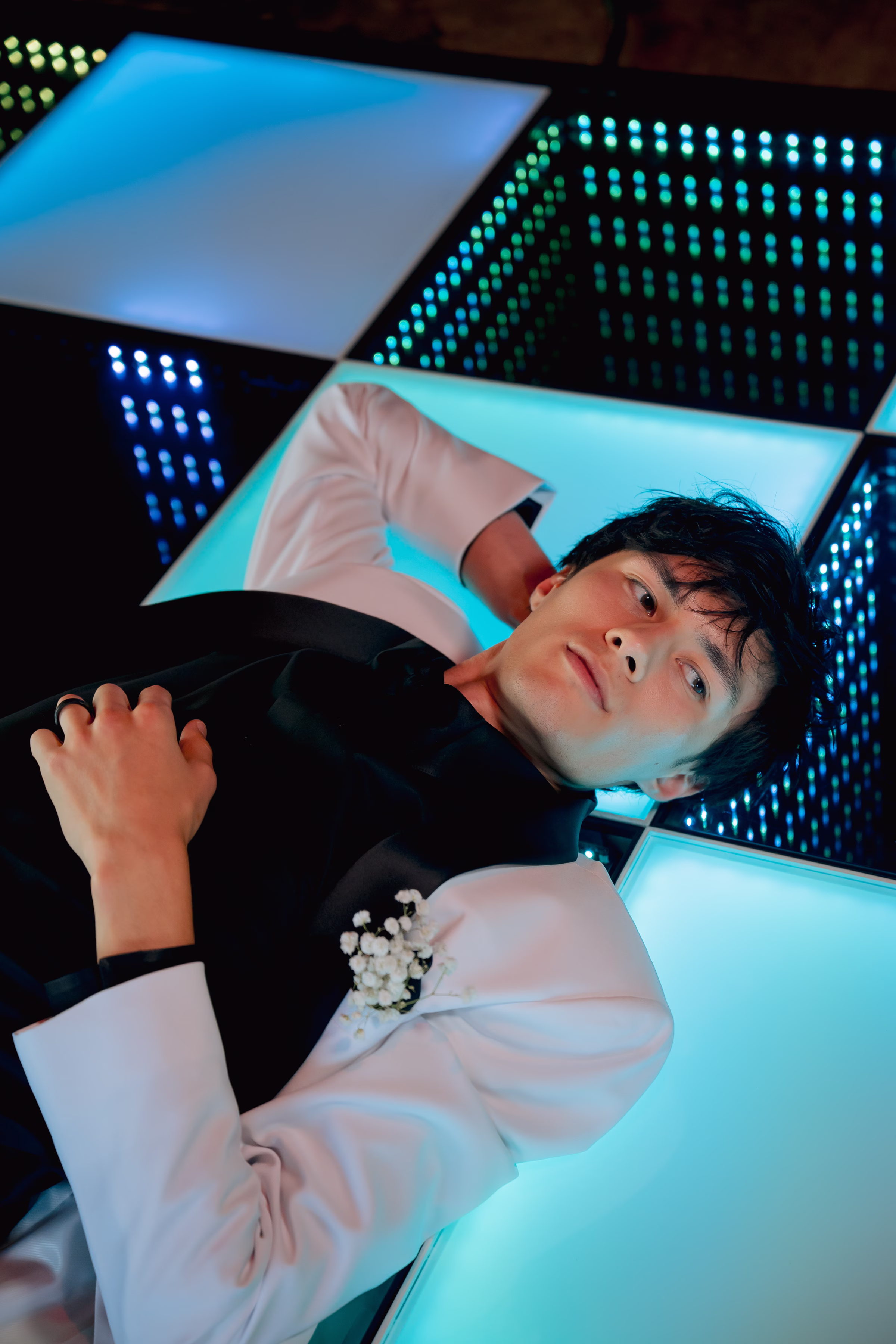 the groom lays on a colorful checkerboard LED dance floor from Record-A-Hit Entertainment