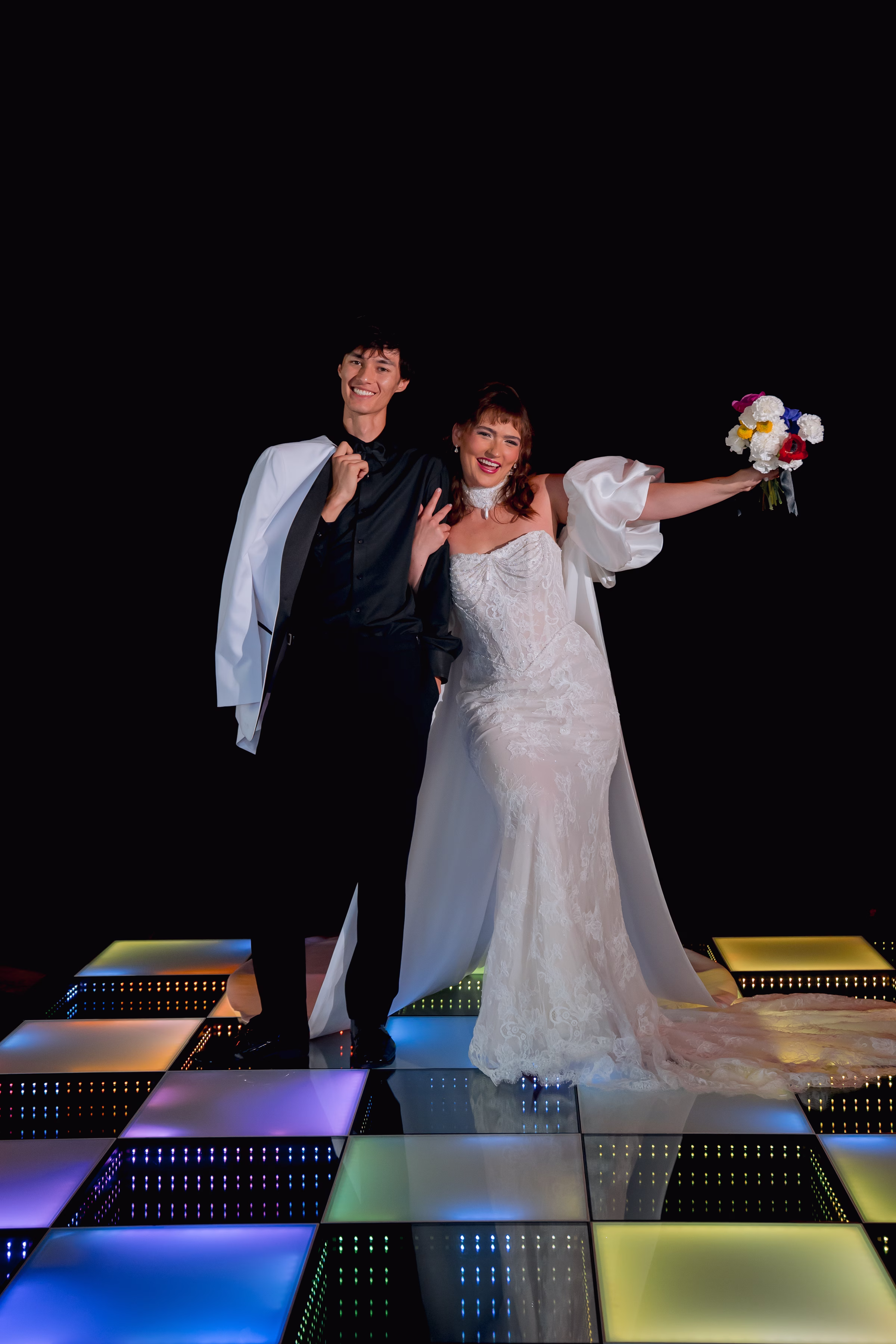 bride and groom models post on a colorful, checkerboard LED dance floor