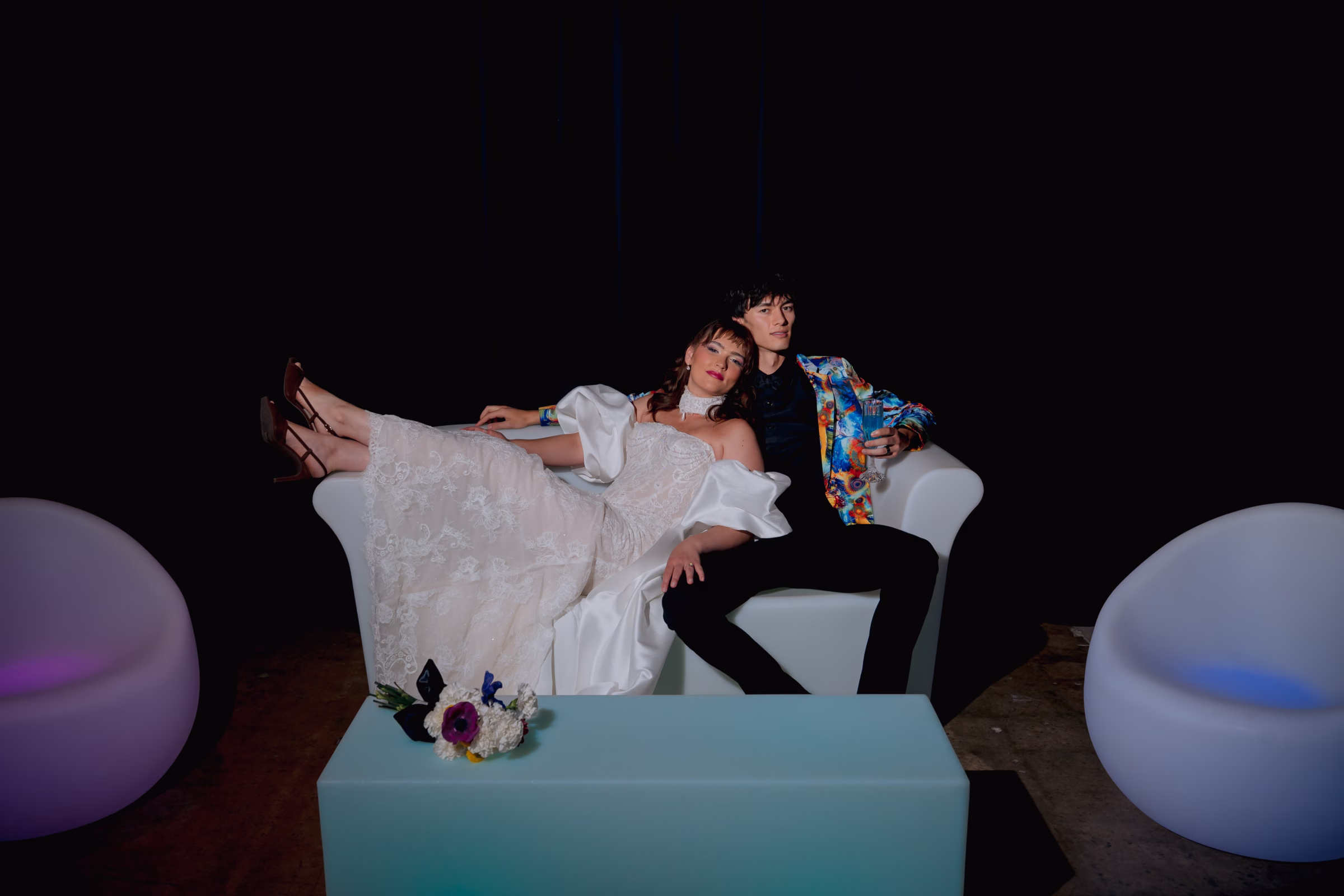 bride and groom models lounge on LED furnishings from Record-A-Hit Entertainment. The bride wears fashions from Miss Ruby Bridal, while the groom debuts a third, colorful suit jack from DuBois Formalwear