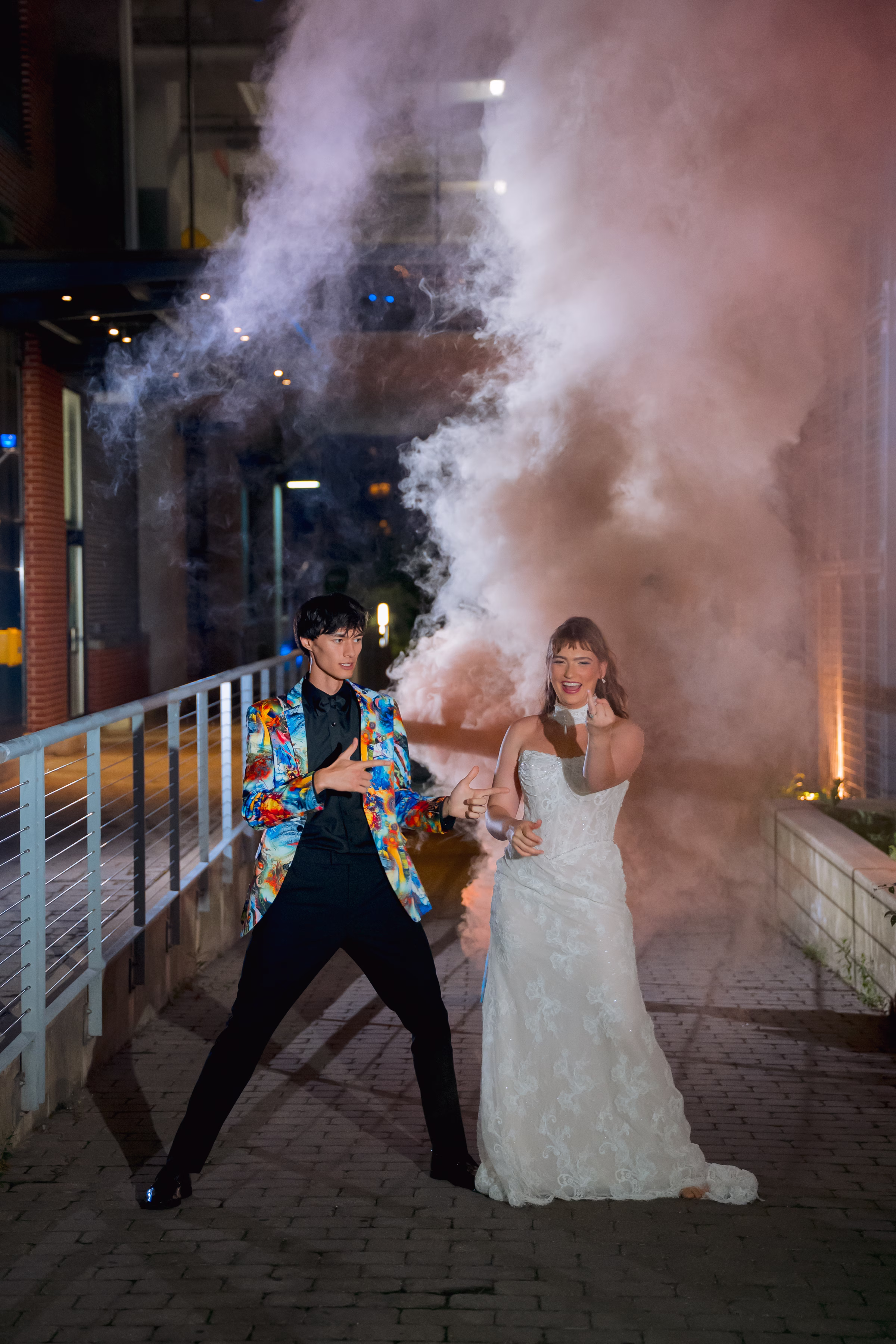 a bride and groom pose with smoke bombs behind them
