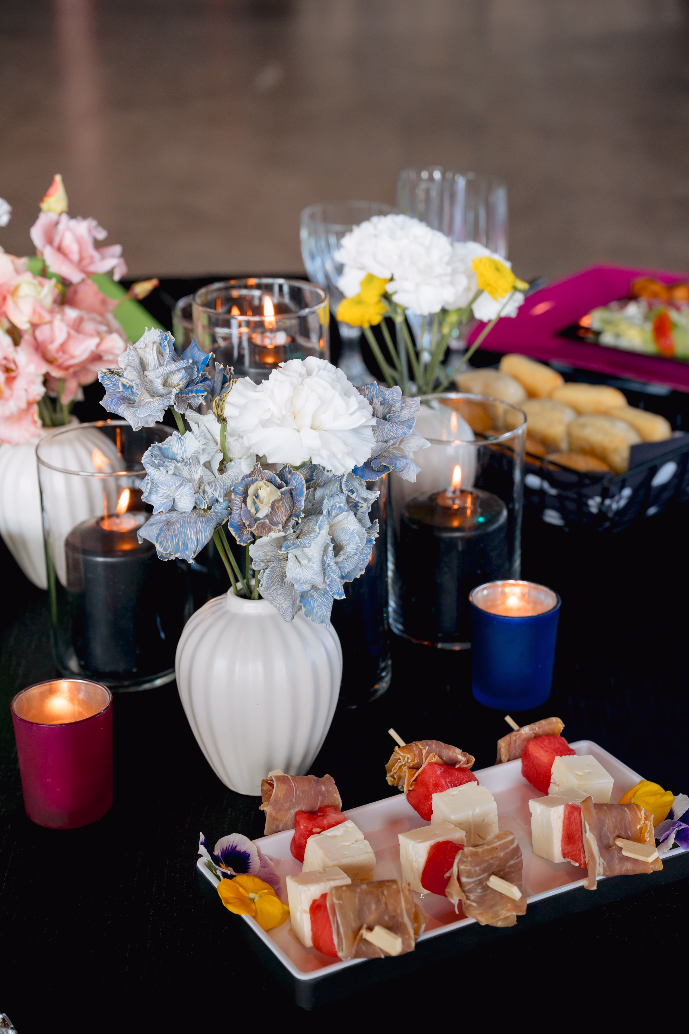 appetizers from Saz's Catering sit on a table beside floral centerpieces and glowing candles