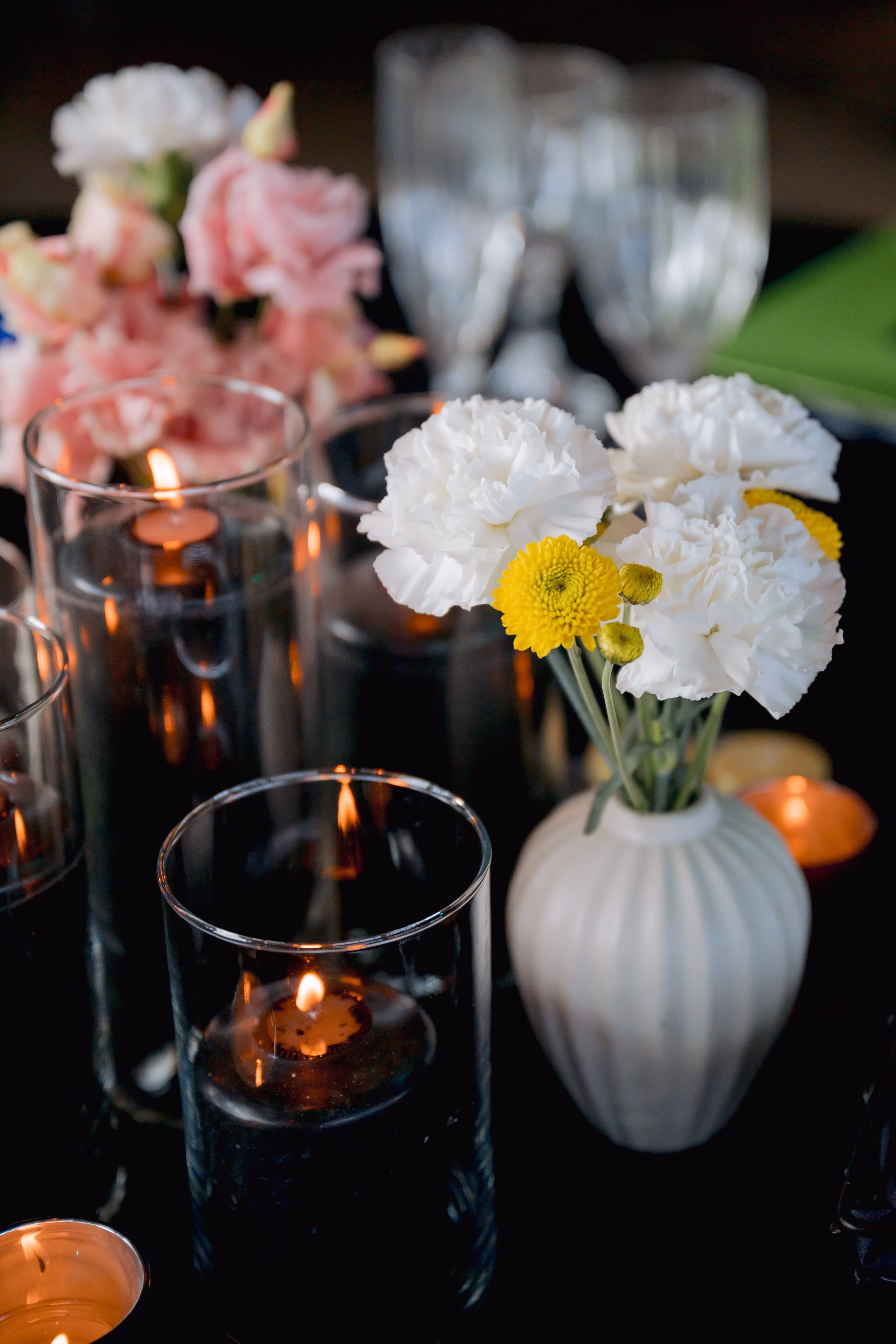 a close-up of floral centerpieces from Flowers for Dreams set beside glowing candles