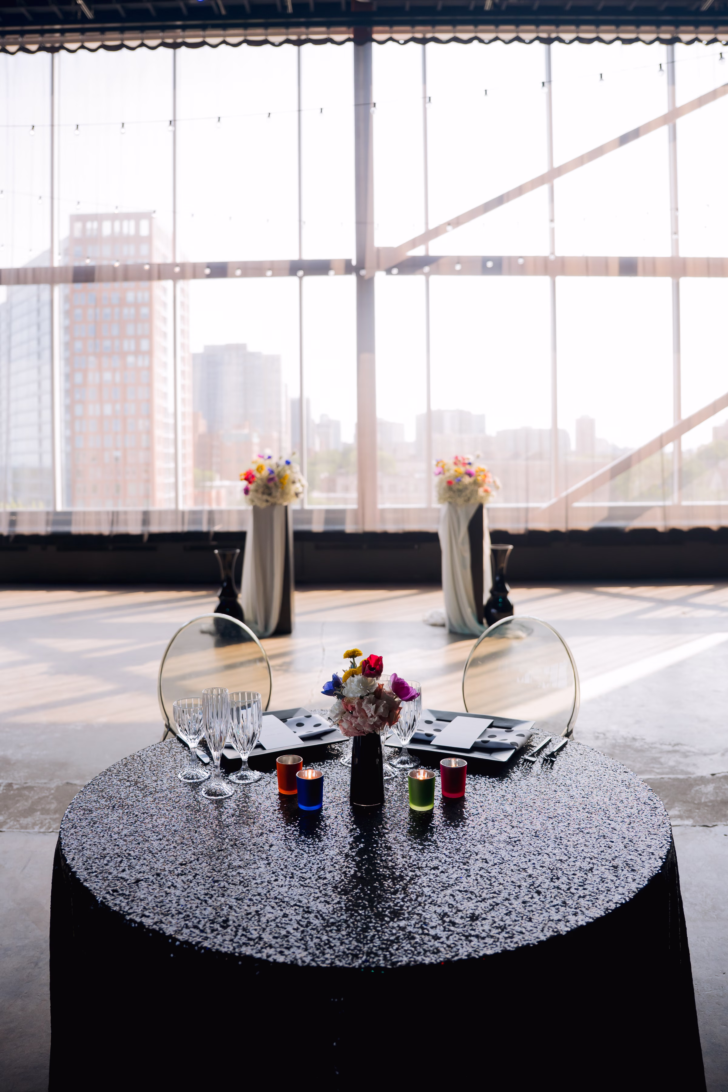 A round sweetheart table draped in a black sequin tablecloth from Windy City Linens and clear acrylic chairs from Tablescape Event Rentals