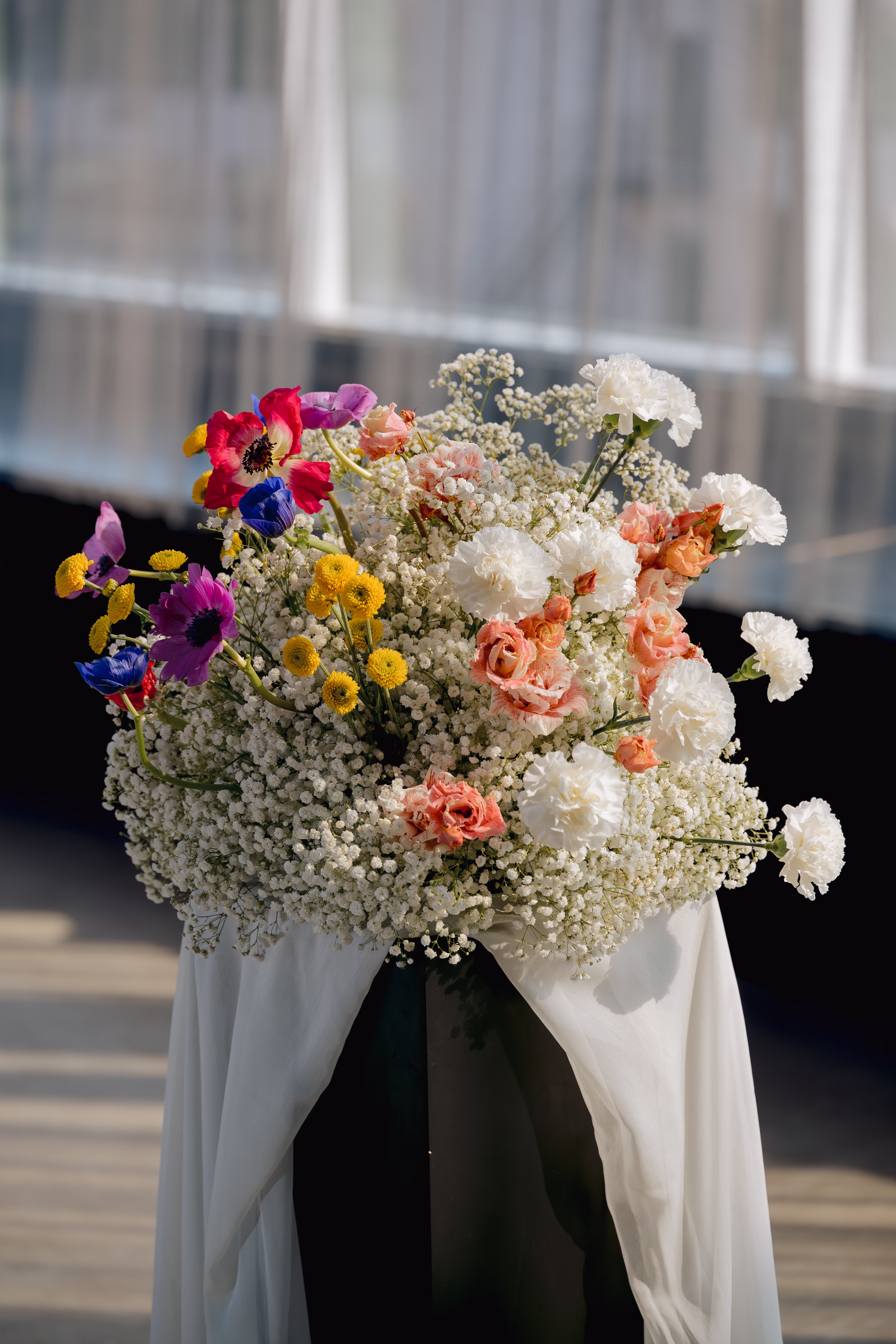 a close-up of the ceremony florals by Flowers for dreams featuring airy baby’s breath and white blooms punctuated with colorful, wildflower-inspired accents in coral, yellow, pink, purple, and blue.