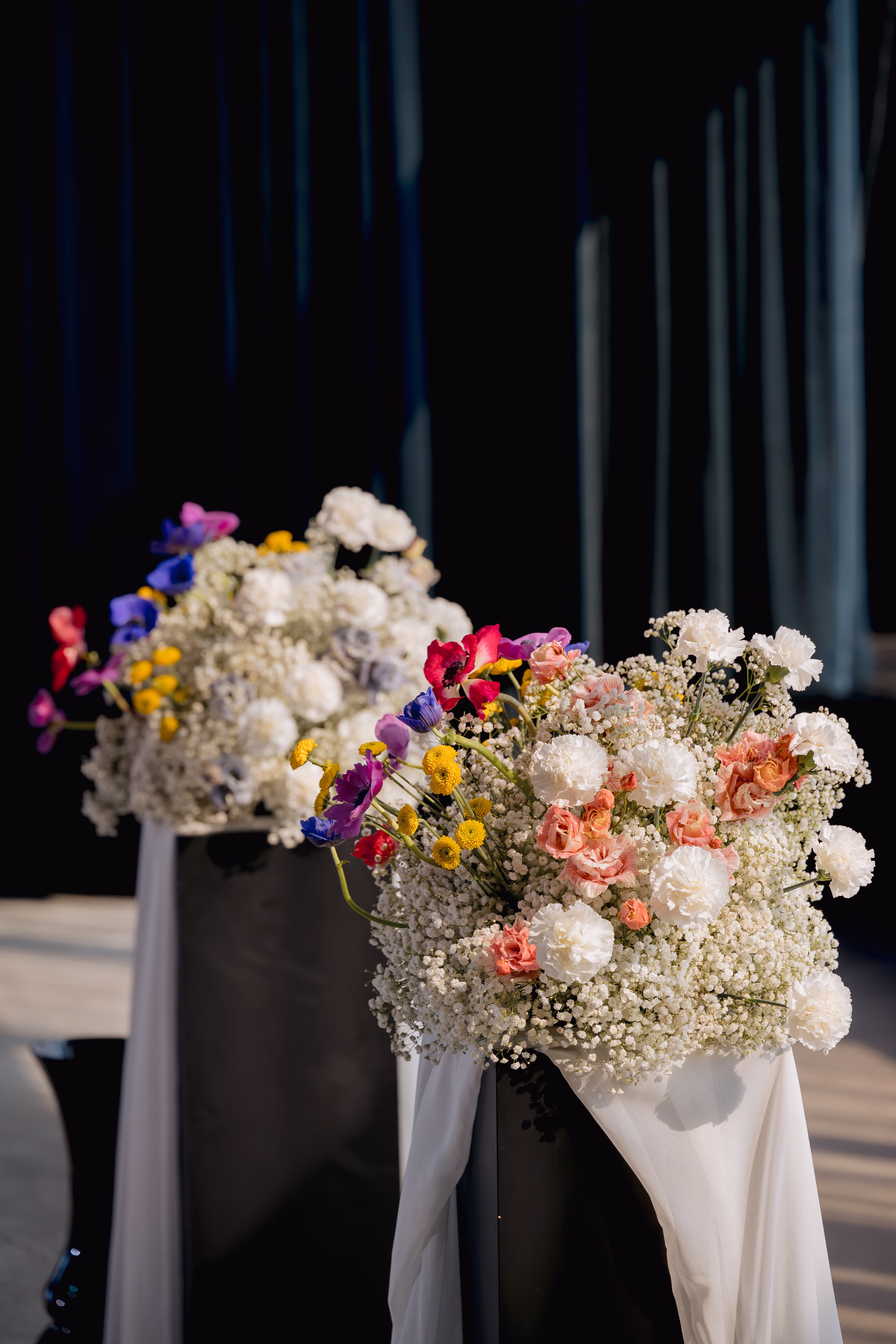 a close-up of the ceremony florals by Flowers for dreams featuring airy baby’s breath and white blooms punctuated with colorful, wildflower-inspired accents in coral, yellow, pink, purple, and blue.