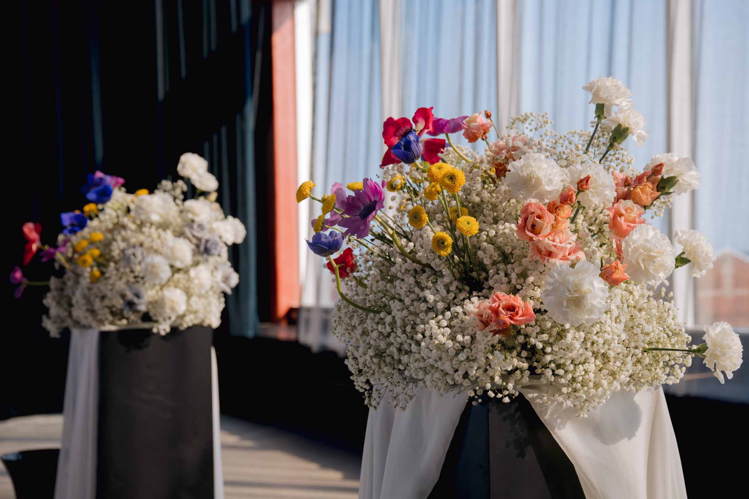 a close-up photo of the ceremony florals by Flowers for Dreams, set atop pillars draped with white cloth