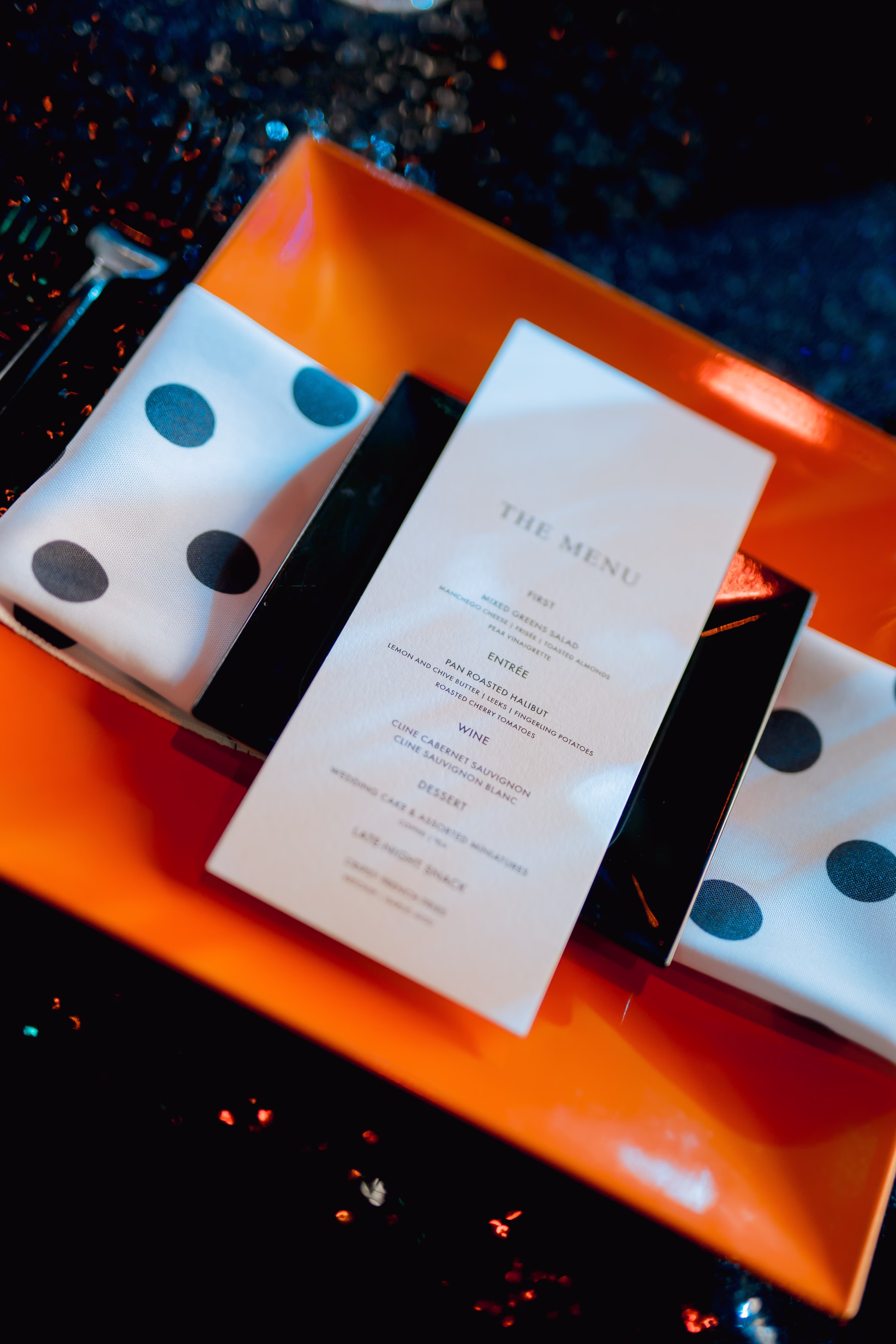 custom wedding menu from Paper Envy, LLC, set on top of square plating from Tablescape Event Rentals and black-and-white polka dot linens from Windy City Linens
