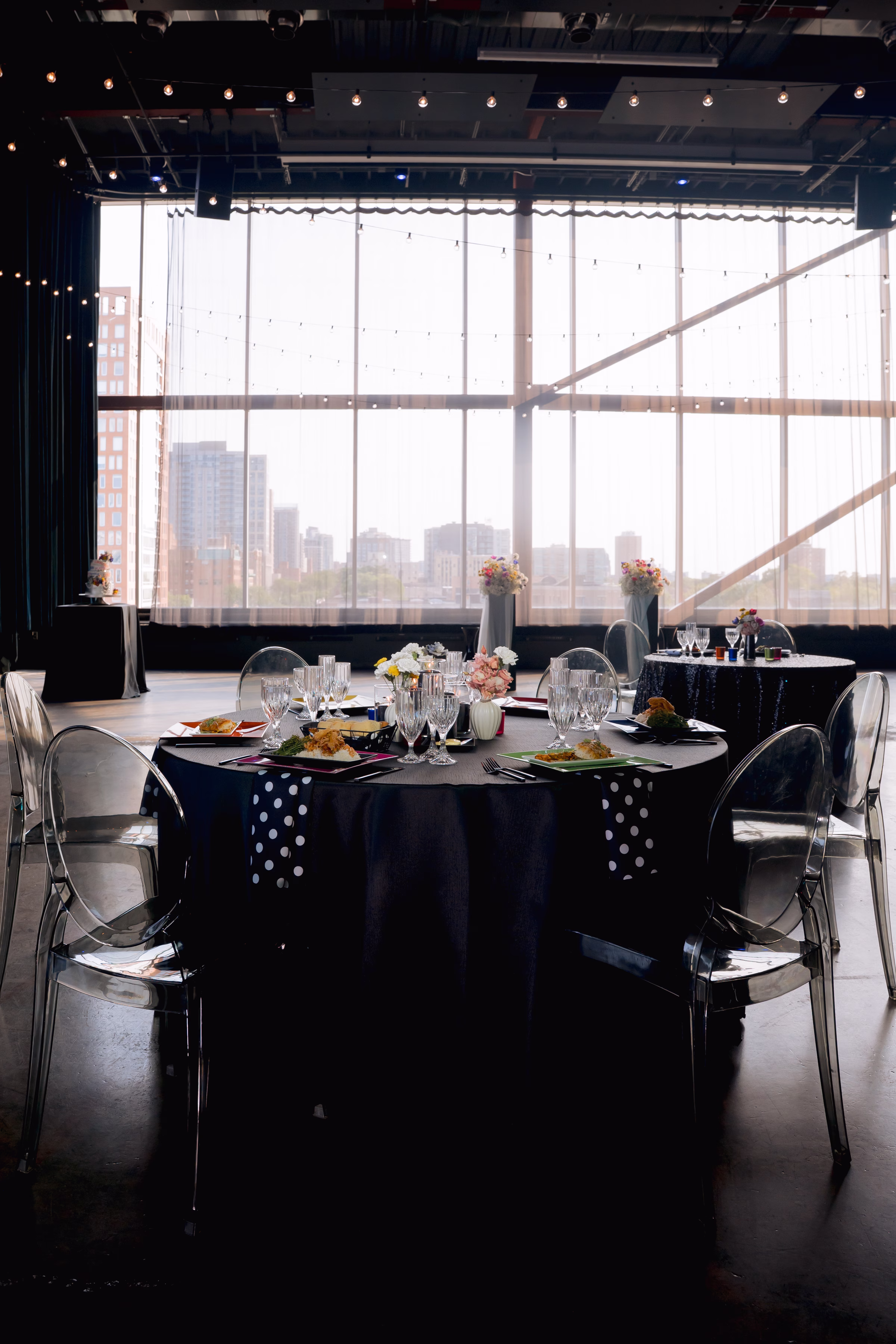 a round reception table draped in a black tablecloth, set against the Milwaukee Skyline views at Jan Serr Studio