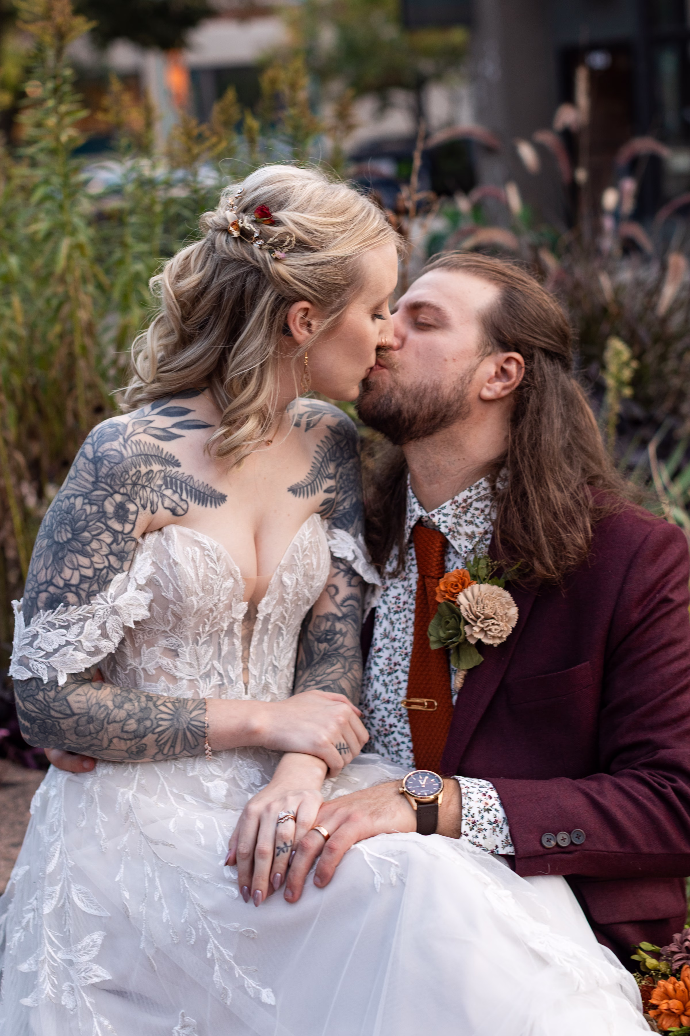 moody romantic fall wedding loft on broadway milwaukee couple portraits 580 0997 - A Moody, Romantic Fall Wedding at The Loft on Broadway | Sarah + Nathan Sarah & Nathan share a kiss surrounded by fall foliage. Sarah's half-updo by Lucent Sky Creations features loose waves twisted in the back and layered with small, colorful florals