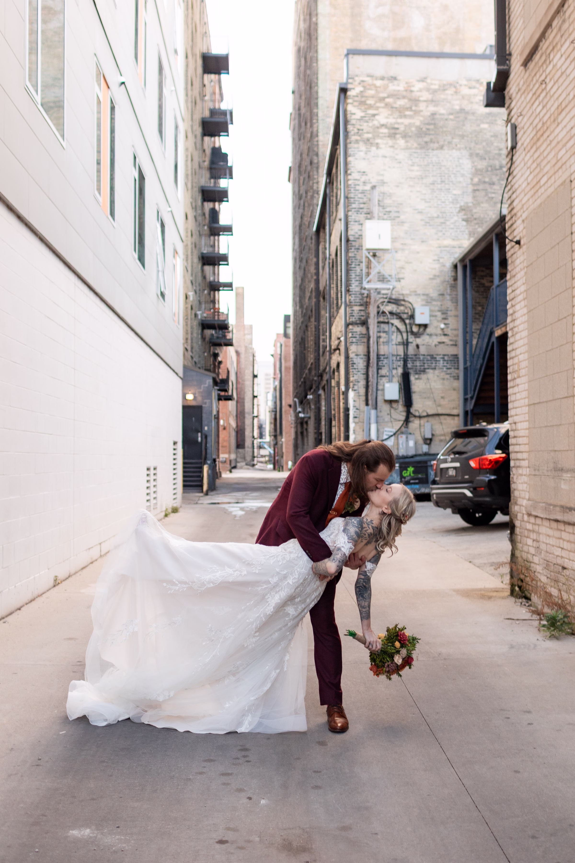 moody romantic fall wedding loft on broadway milwaukee couple portraits 592 11204 - A Moody, Romantic Fall Wedding at The Loft on Broadway | Sarah + Nathan a newly wedding couple share a dip kiss in an alleyway in downtown Milwaukee, Wisconsin