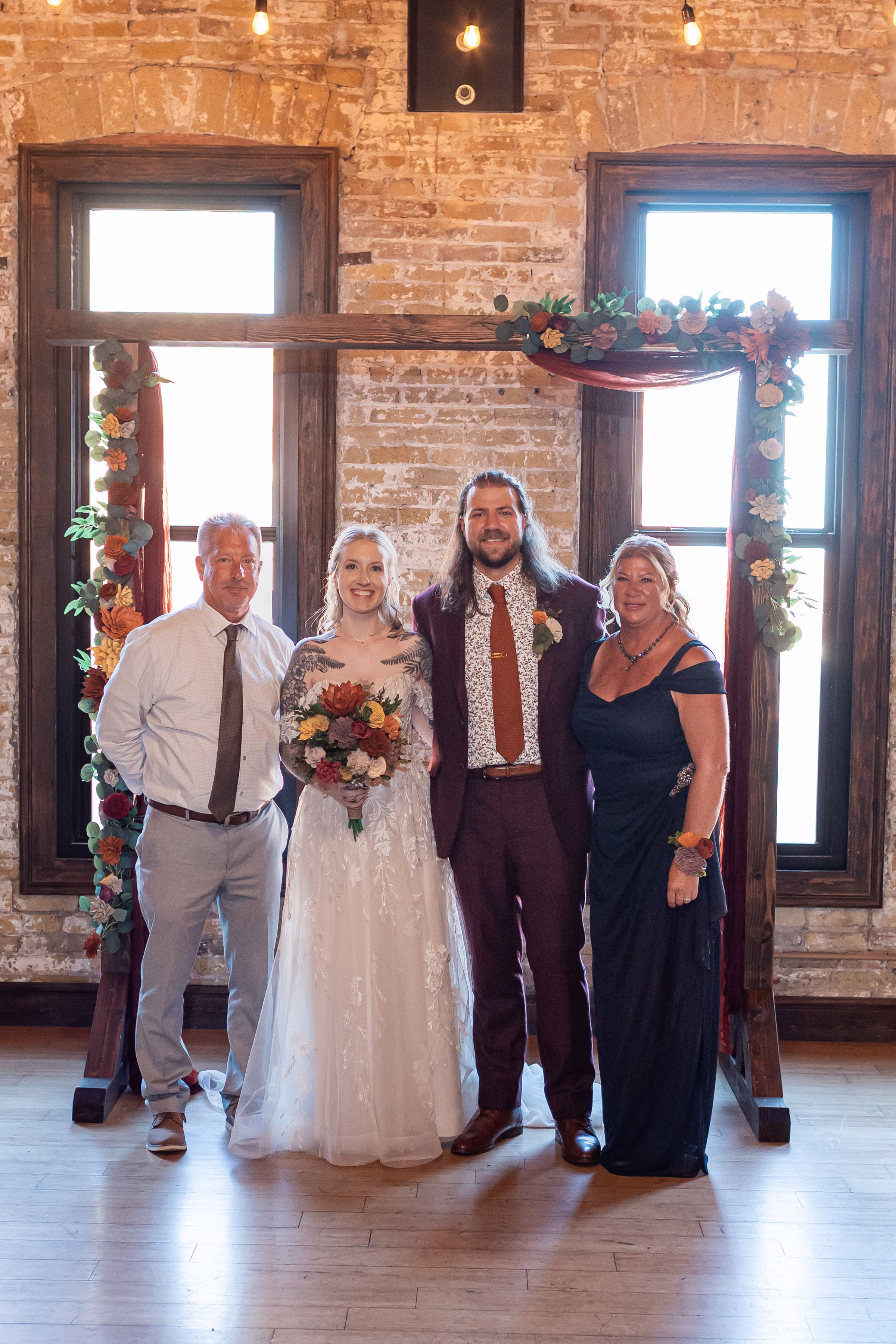 moody romantic fall wedding loft on broadway milwaukee group portraits 504 10967 - A Moody, Romantic Fall Wedding at The Loft on Broadway | Sarah + Nathan a bride and groom pose for family photos in front of their ceremony backdrop in Milwaukee, Wisconsin