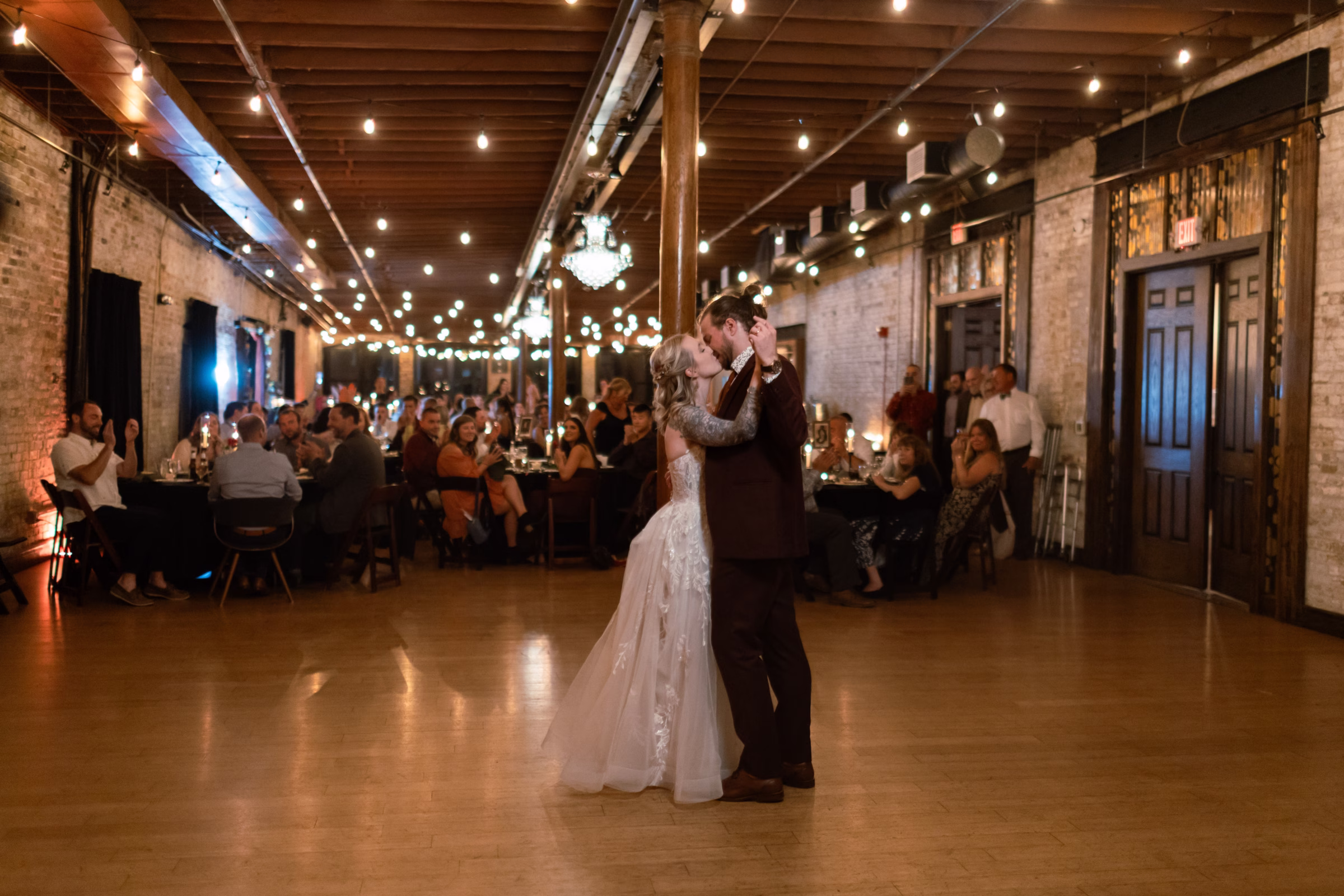 moody romantic fall wedding loft on broadway milwaukee reception dancing 800 1349 - A Moody, Romantic Fall Wedding at The Loft on Broadway | Sarah + Nathan a couple kisses while sharing a first dance at their wedding at The Loft on Broadway in Milwaukee's historic Third Ward