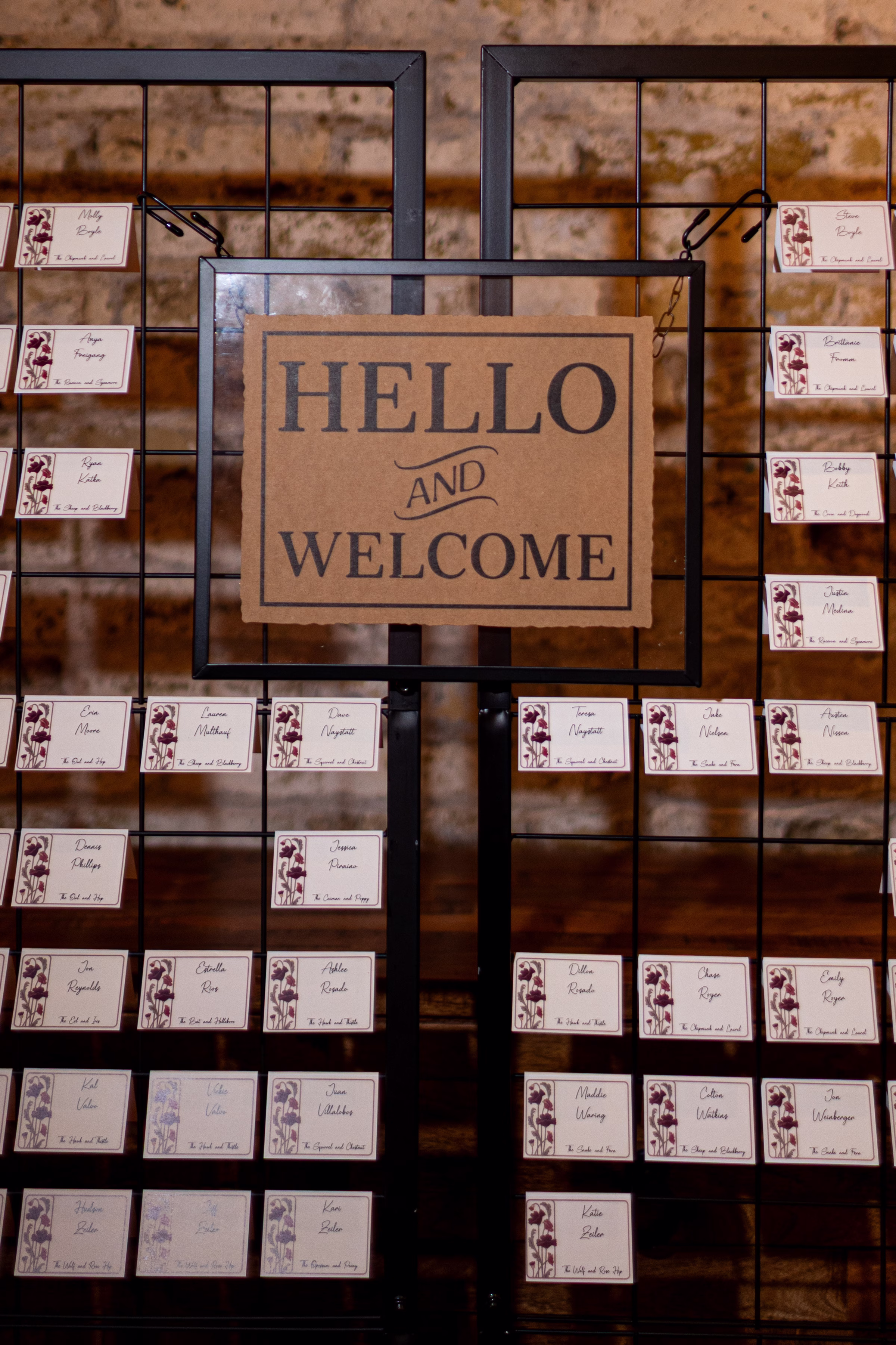 moody romantic fall wedding loft on broadway milwaukee reception signage 393 0655 - A Moody, Romantic Fall Wedding at The Loft on Broadway | Sarah + Nathan a seating chart that says "Hello and Welcome," with name cards draped between the rungs of a welded black fence display