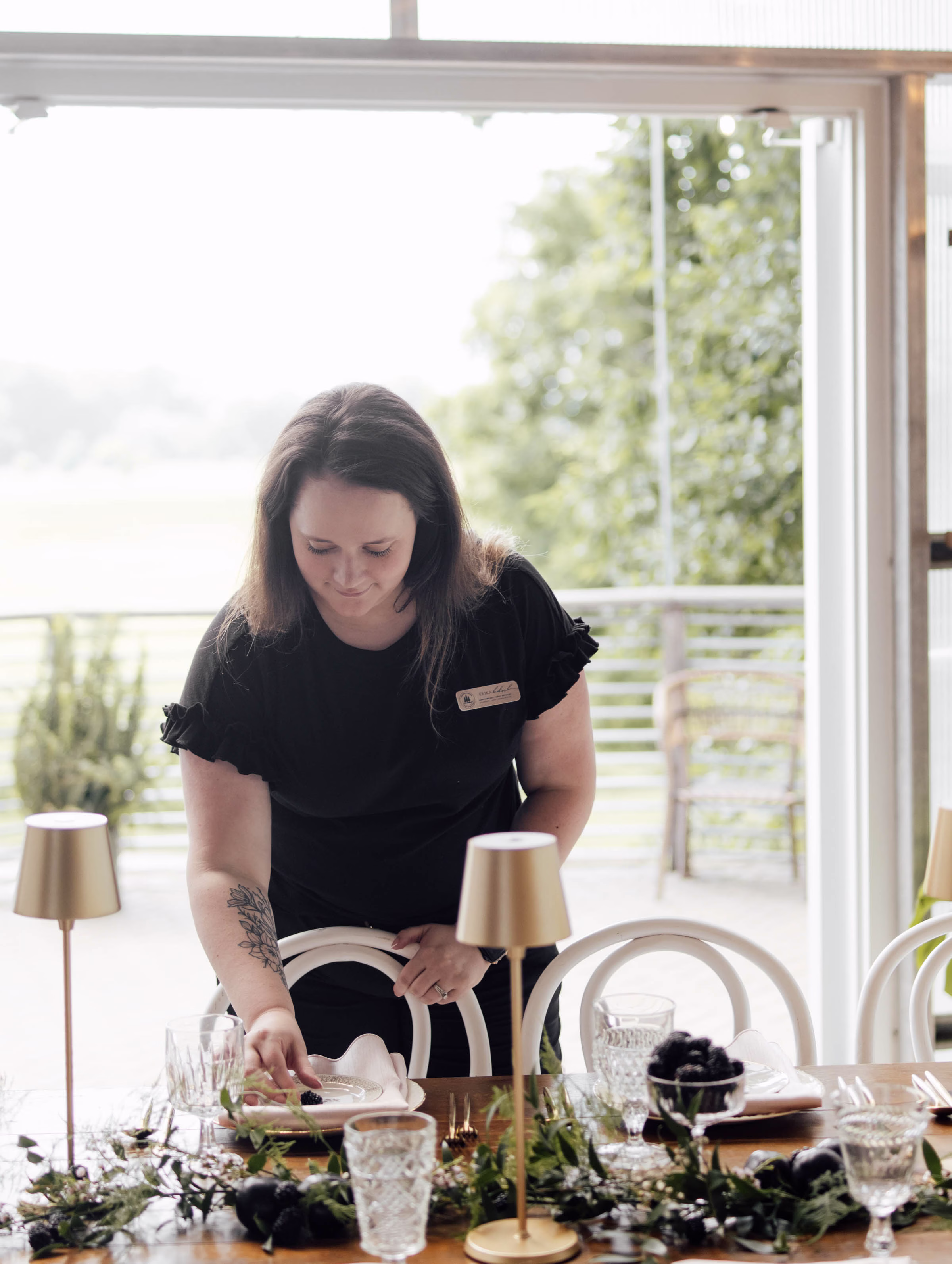 Wisconsin wedding planner from Northwoods Event Services carefully styling a reception table setting, placing fresh fruit accents onto dinner plates ahead of the event.
