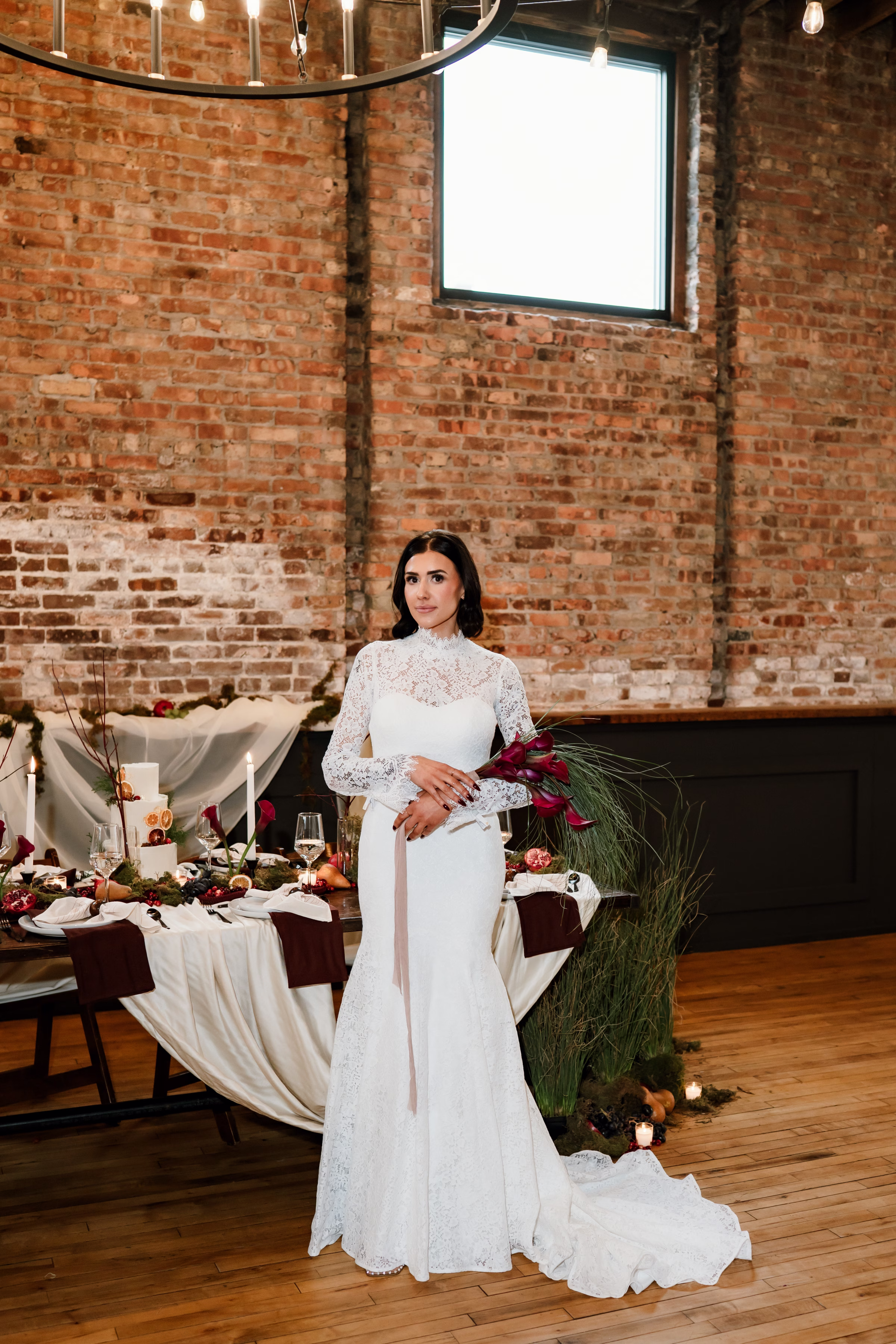 rich velvet fall wedding inspiration mercantile hall burlington wisconsin tablescape bride florals 198 - Rich Velvet Fall Wedding Inspiration at Mercantile Hall in Burlington, Wisconsin a bride stands at a fall wedding tablescape at Mercantile Hall. She is holding a bouquet from The Flower Bar, and is wearing a vintage inspired wedding dress from Bon Bon Belle Bridal Boutique.