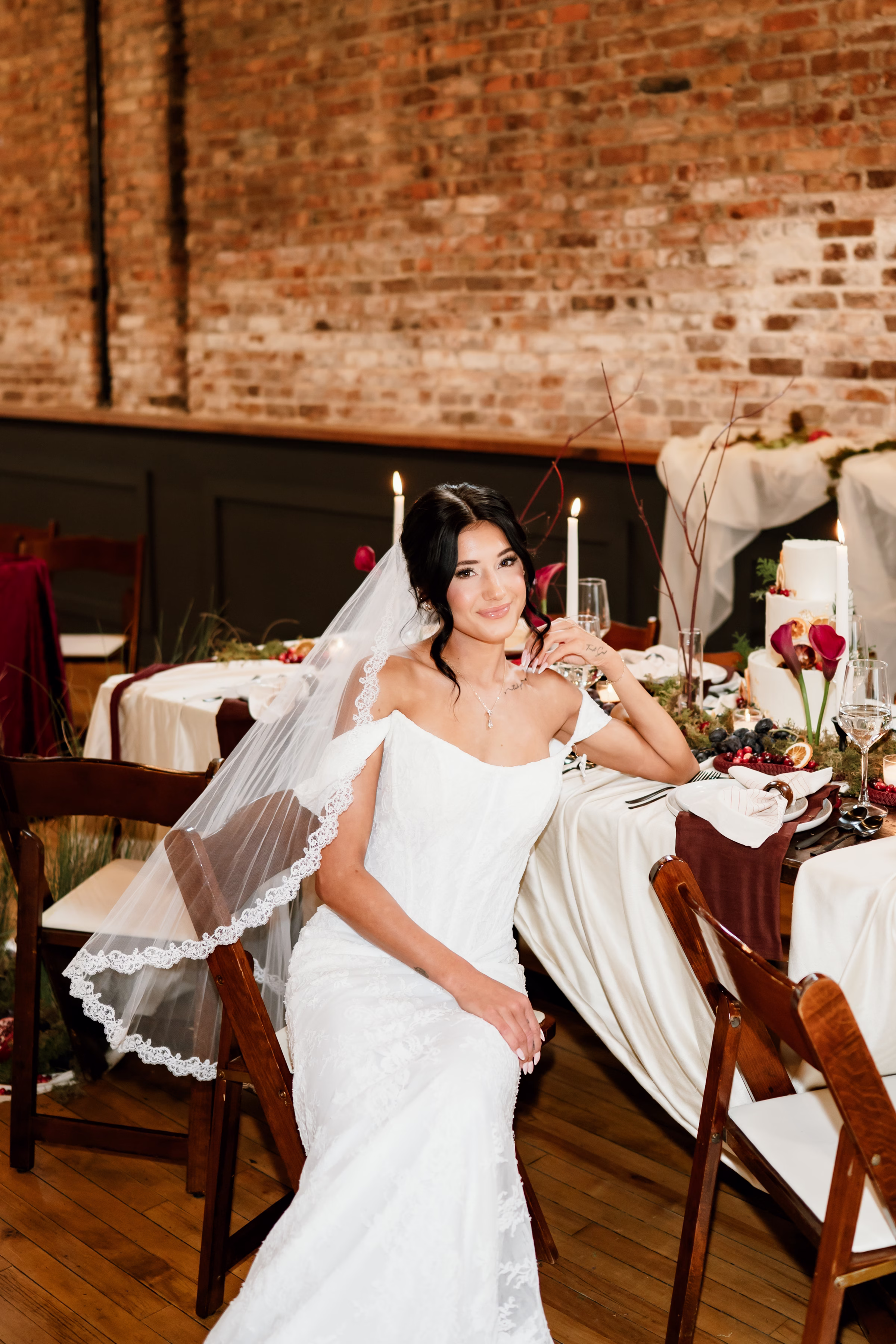 rich velvet fall wedding inspiration mercantile hall burlington wisconsin tablescape bride florals 99 - Rich Velvet Fall Wedding Inspiration at Mercantile Hall in Burlington, Wisconsin a bride sits at a reception table wearing a statuesque, lace gown from Bon Bon Belle Bridal Boutique. She is accessorized with a fingertip-length tulle veil with embroidered edges