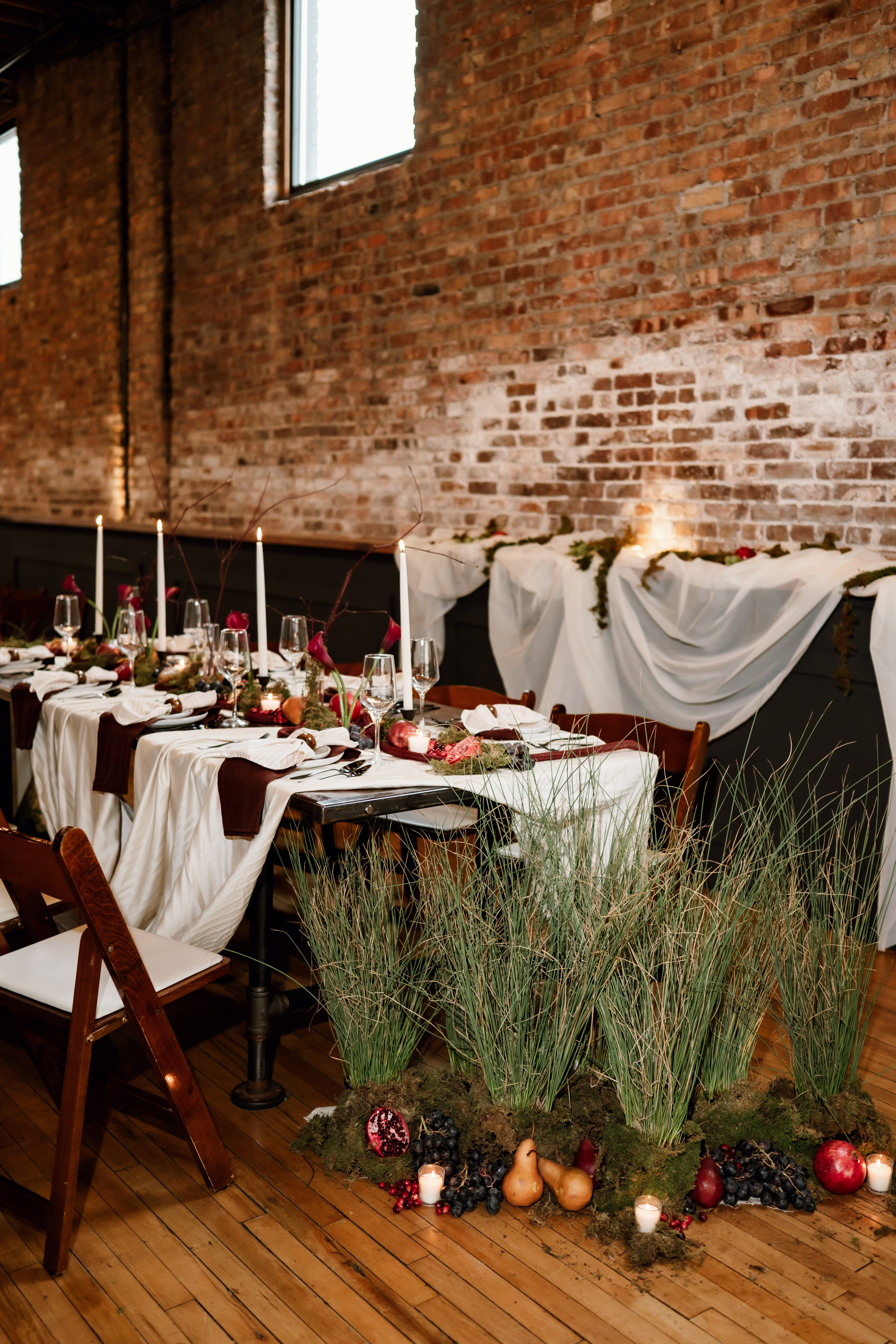 rich velvet fall wedding inspiration mercantile hall burlington wisconsin tablescape decor florals 23 - Rich Velvet Fall Wedding Inspiration at Mercantile Hall in Burlington, Wisconsin trendy fruit as décor including pears, pomegranates, oranges, and grapefruit, and mossy grasses from The Flower Bar and Anna's Florals artfully arranged at the end of a wedding reception table