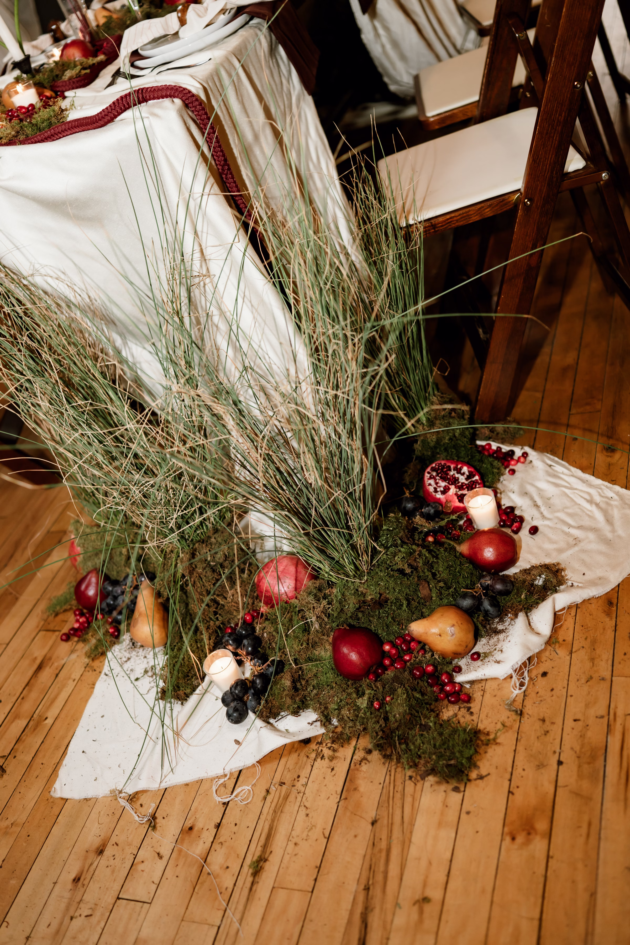 rich velvet fall wedding inspiration mercantile hall burlington wisconsin tablescape decor florals 33 - Rich Velvet Fall Wedding Inspiration at Mercantile Hall in Burlington, Wisconsin trendy fruit as décor and mossy grasses from The Flower Bar and Anna's Florals artfully arranged at the end of a reception table. Fruits include pears, apples, pomegranates, and grapes