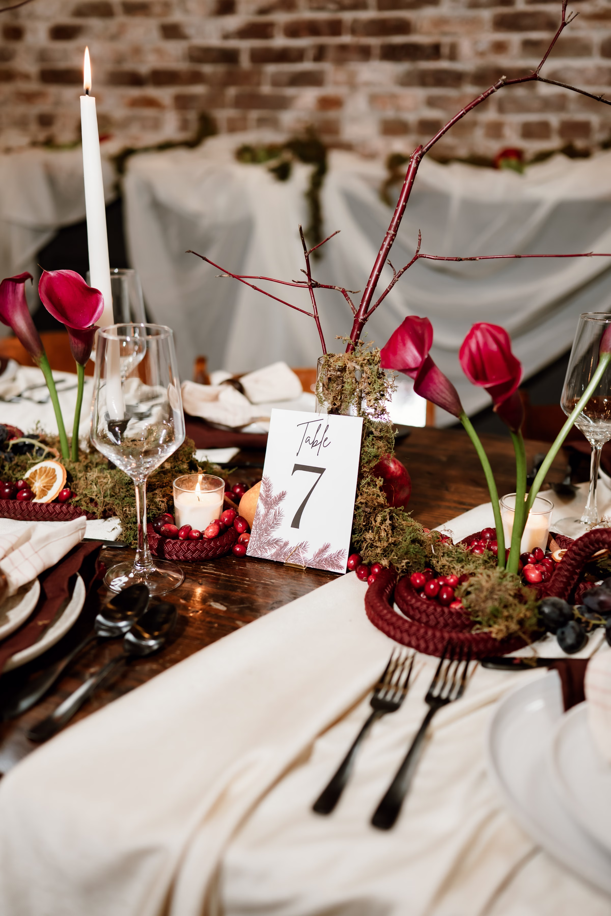 rich velvet fall wedding inspiration mercantile hall burlington wisconsin tablescape decor florals 37 - Rich Velvet Fall Wedding Inspiration at Mercantile Hall in Burlington, Wisconsin a close-up of a wedding reception table number by Jaime Rose Coordination & DIY surrounded by candles, burgundy calla lilies, moss, and fruit as décor